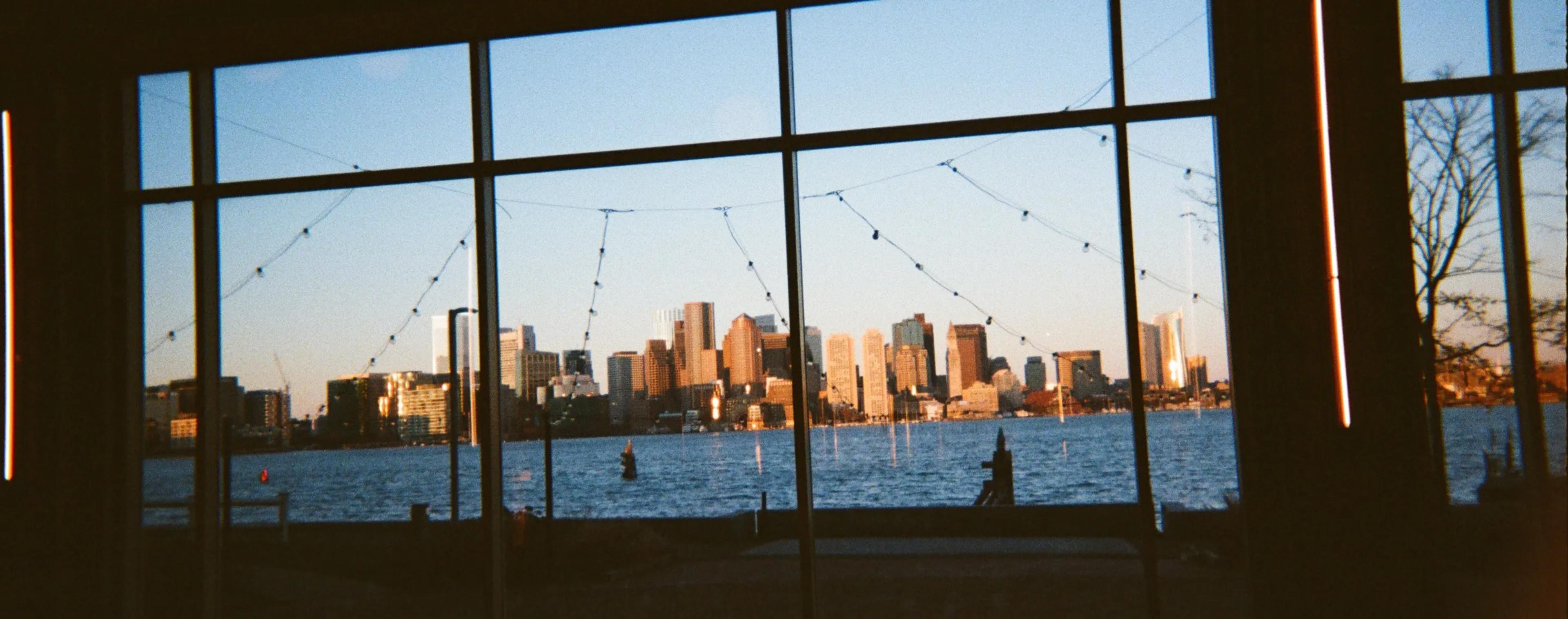 The Boston skyline seen through a wall of studio windows at sunset