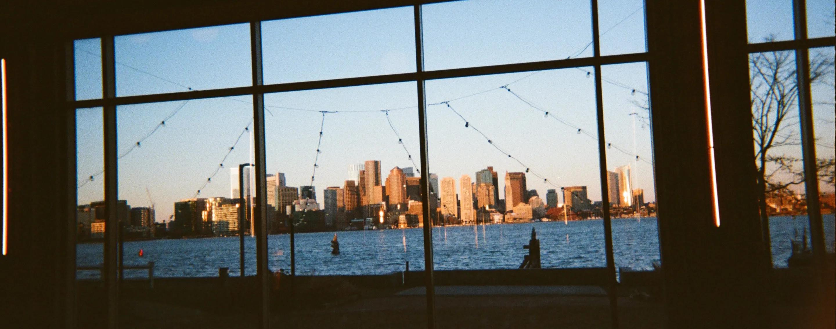 The Boston skyline seen through a wall of studio windows at sunset