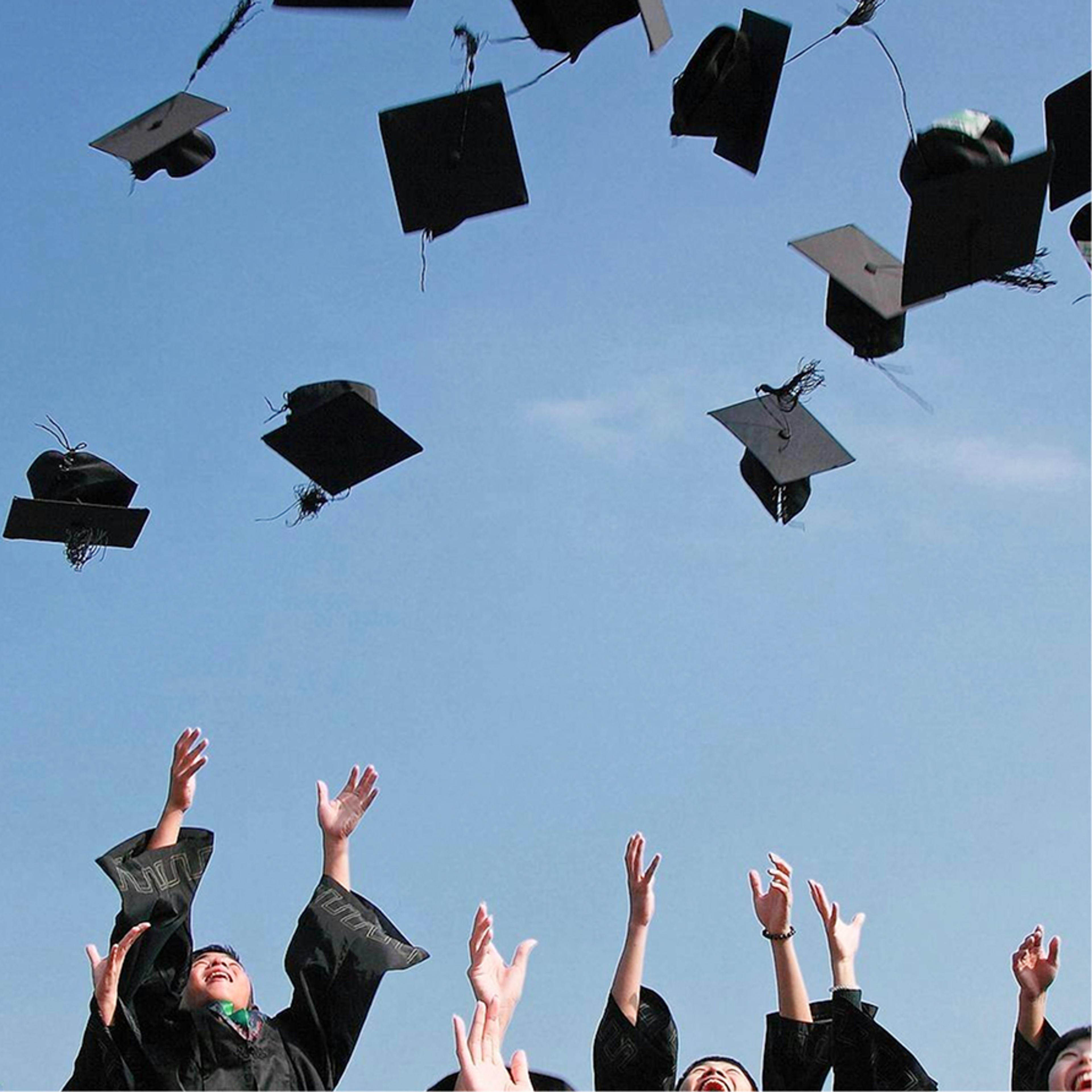 Graduates throwing their caps into a clear blue sky