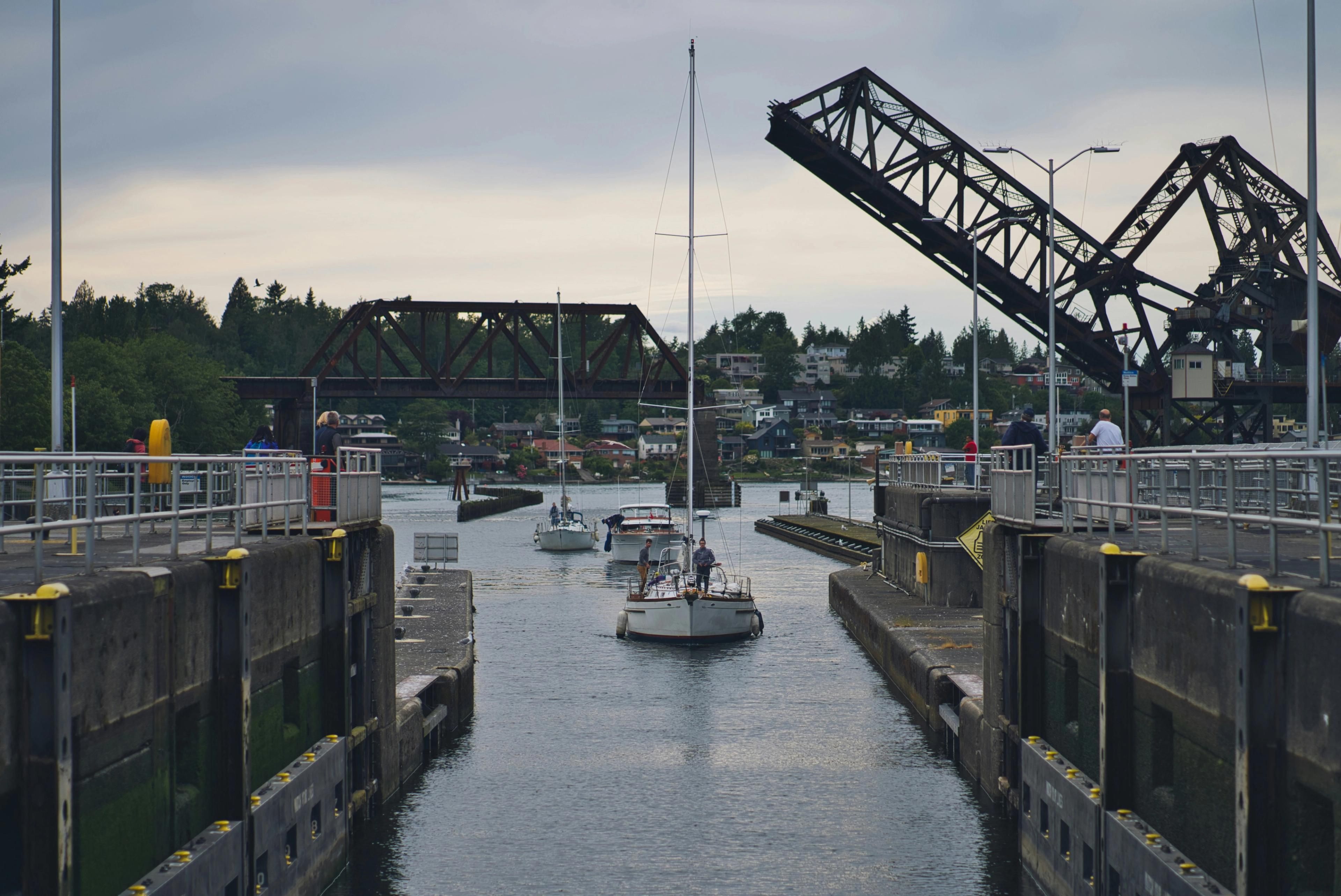A sailboat in the Ballard Locks in Seattle, with a raised railway bridge behind
