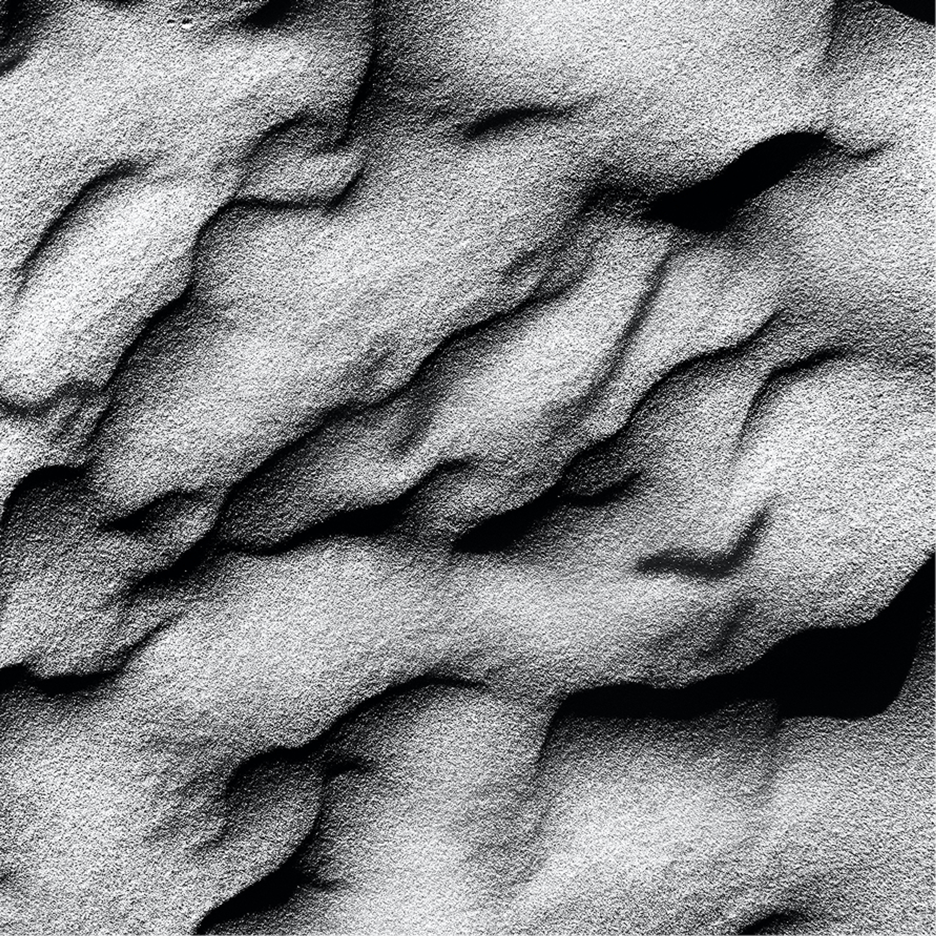 A close-up of wind-rippled sand in black and white