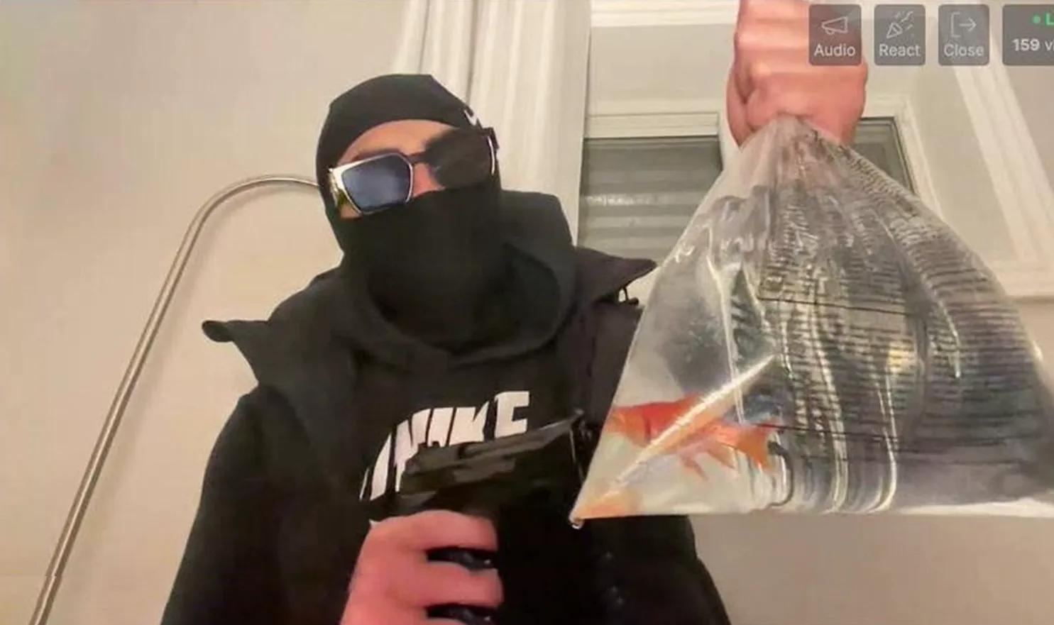 Un homme tient un pistolet prêt à tirer sur un poisson rouge. 