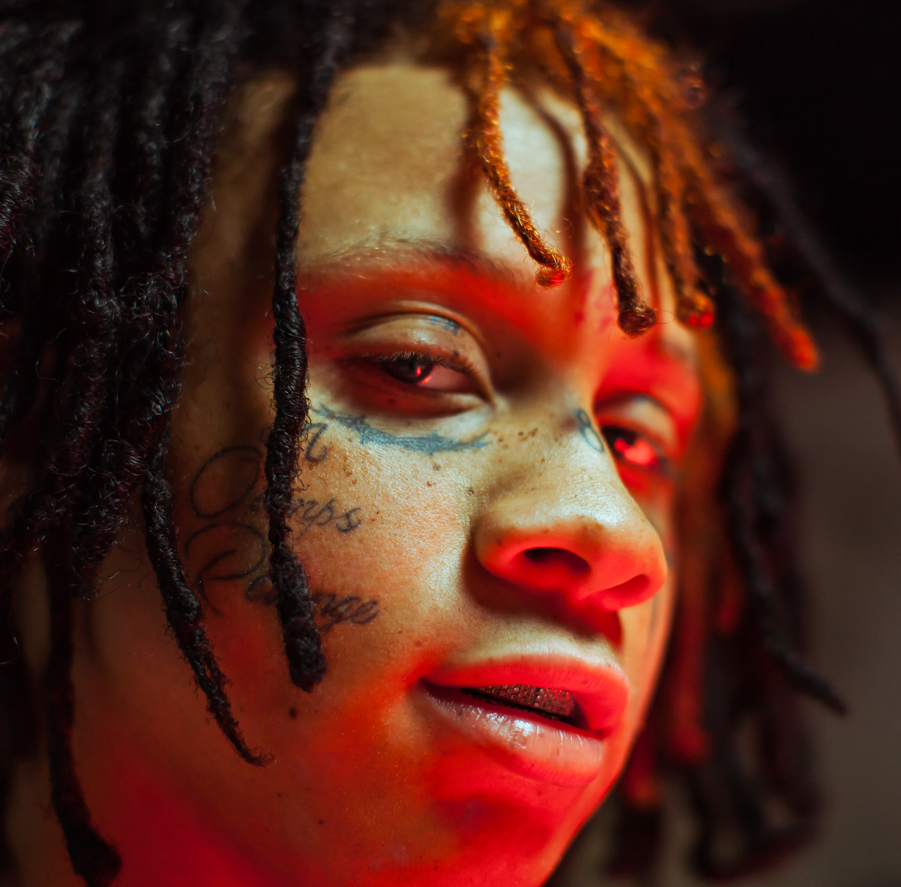 Trippie Redd looking into camera, red light glowing from below