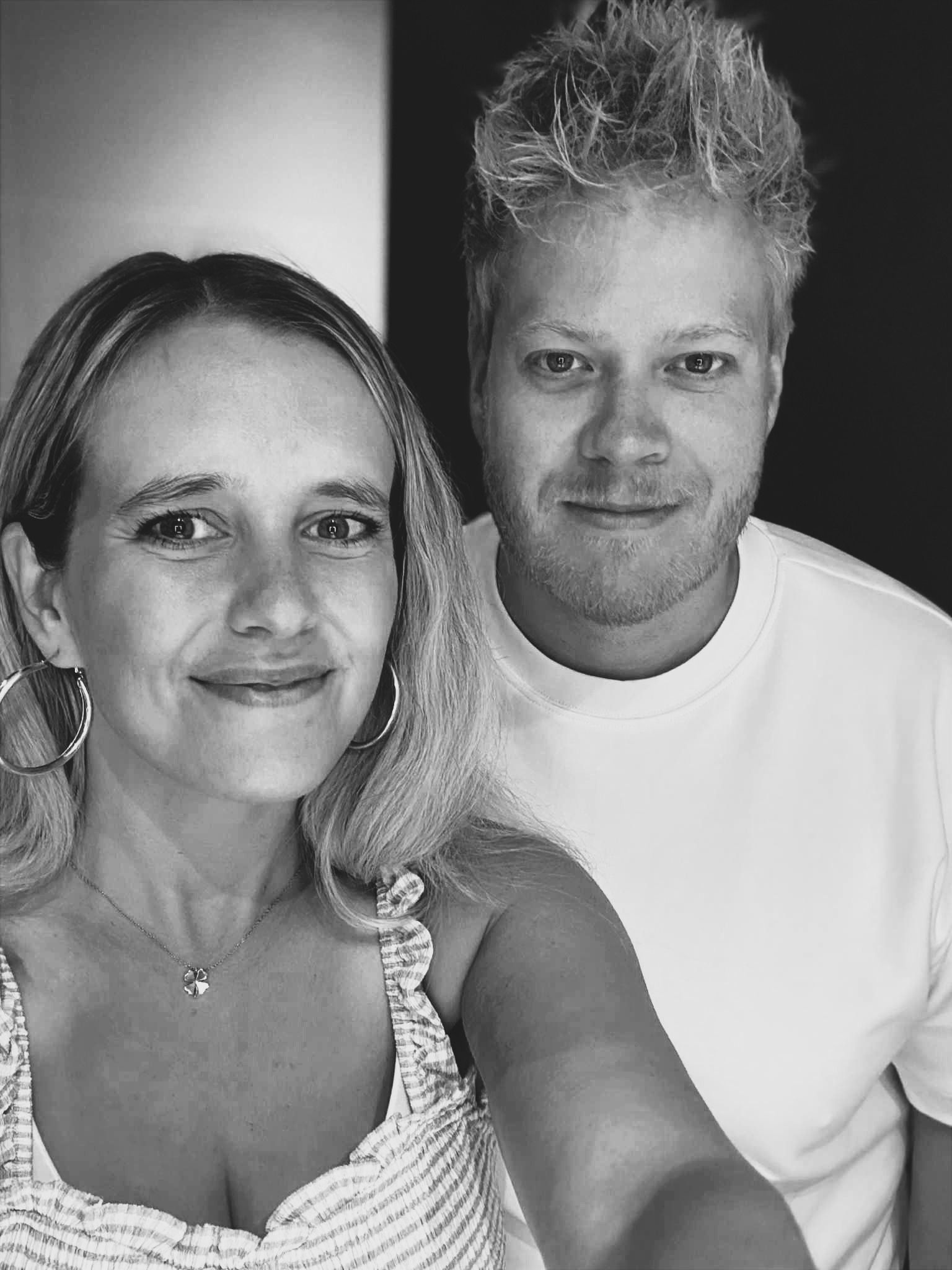 A man and a woman smile in a black and white selfie