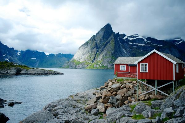 Red traditional house on the edge of a mountainous lake.