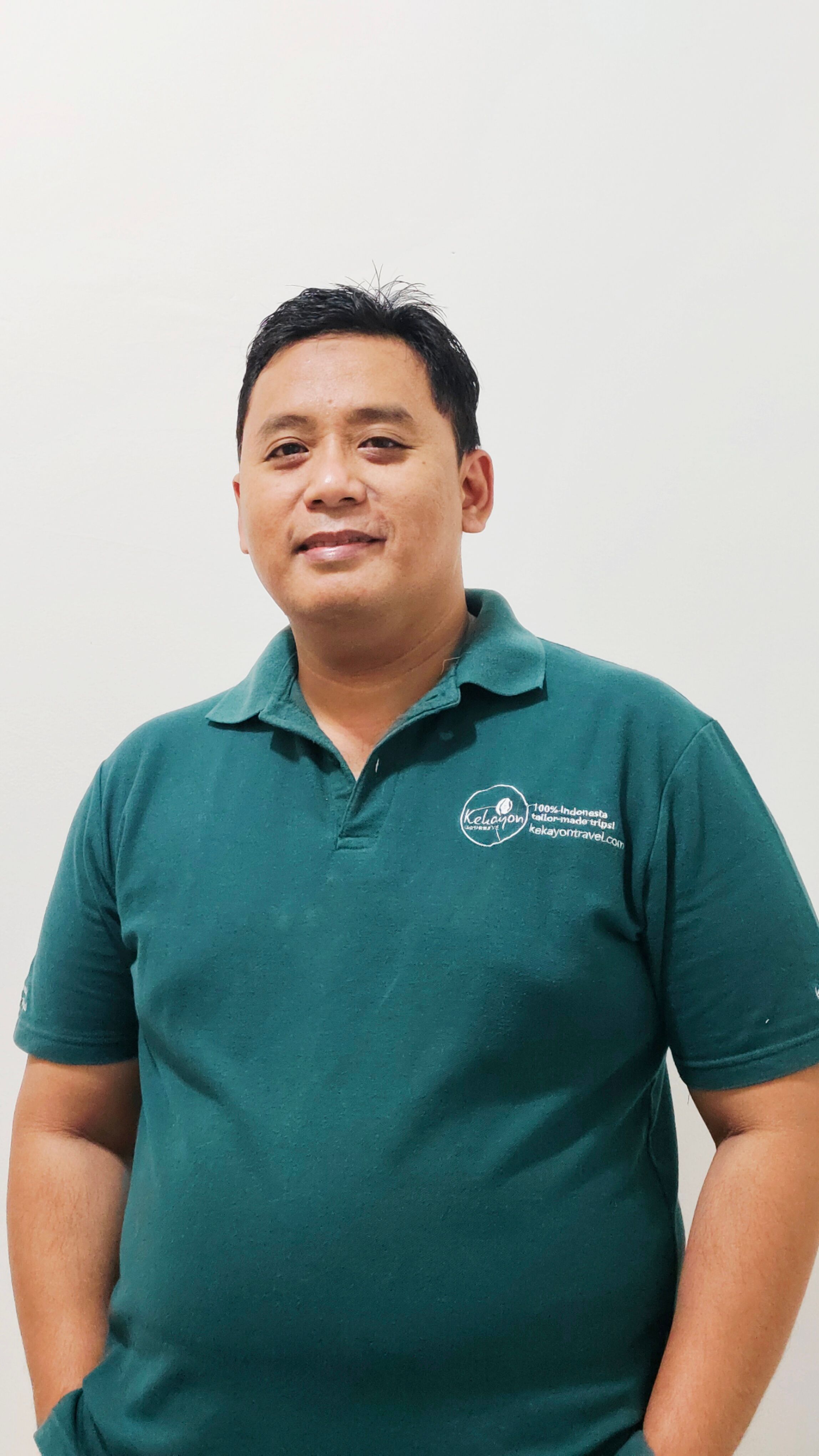 Smiling Indonesian man with his hands in his pockets and green t-shirt