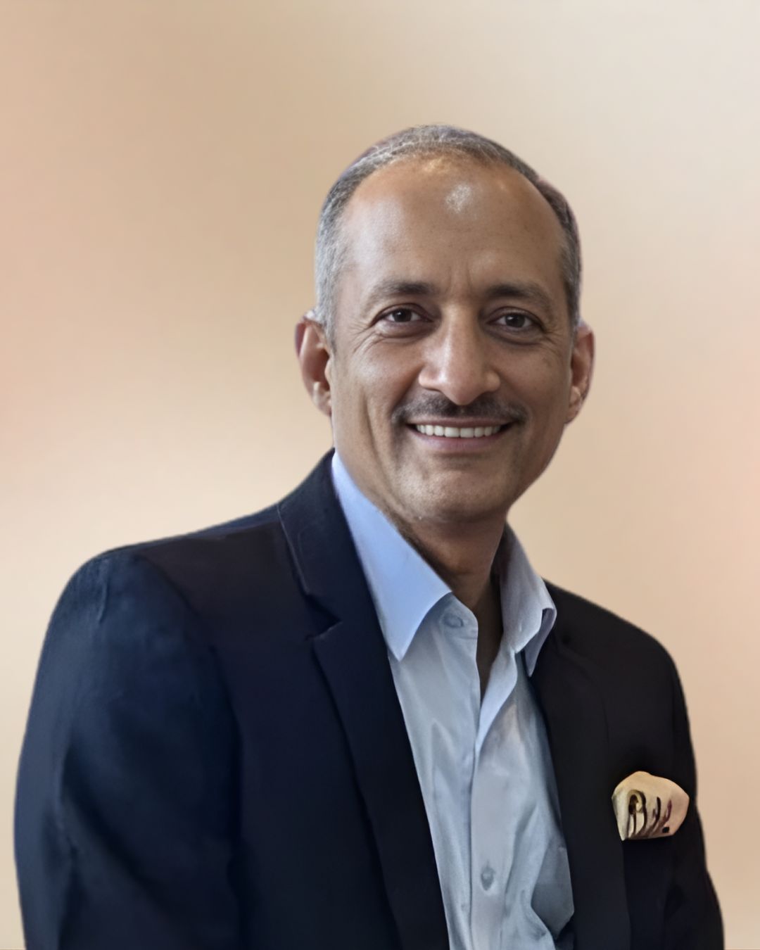 A smiling man in a blue suit jacket with moustache