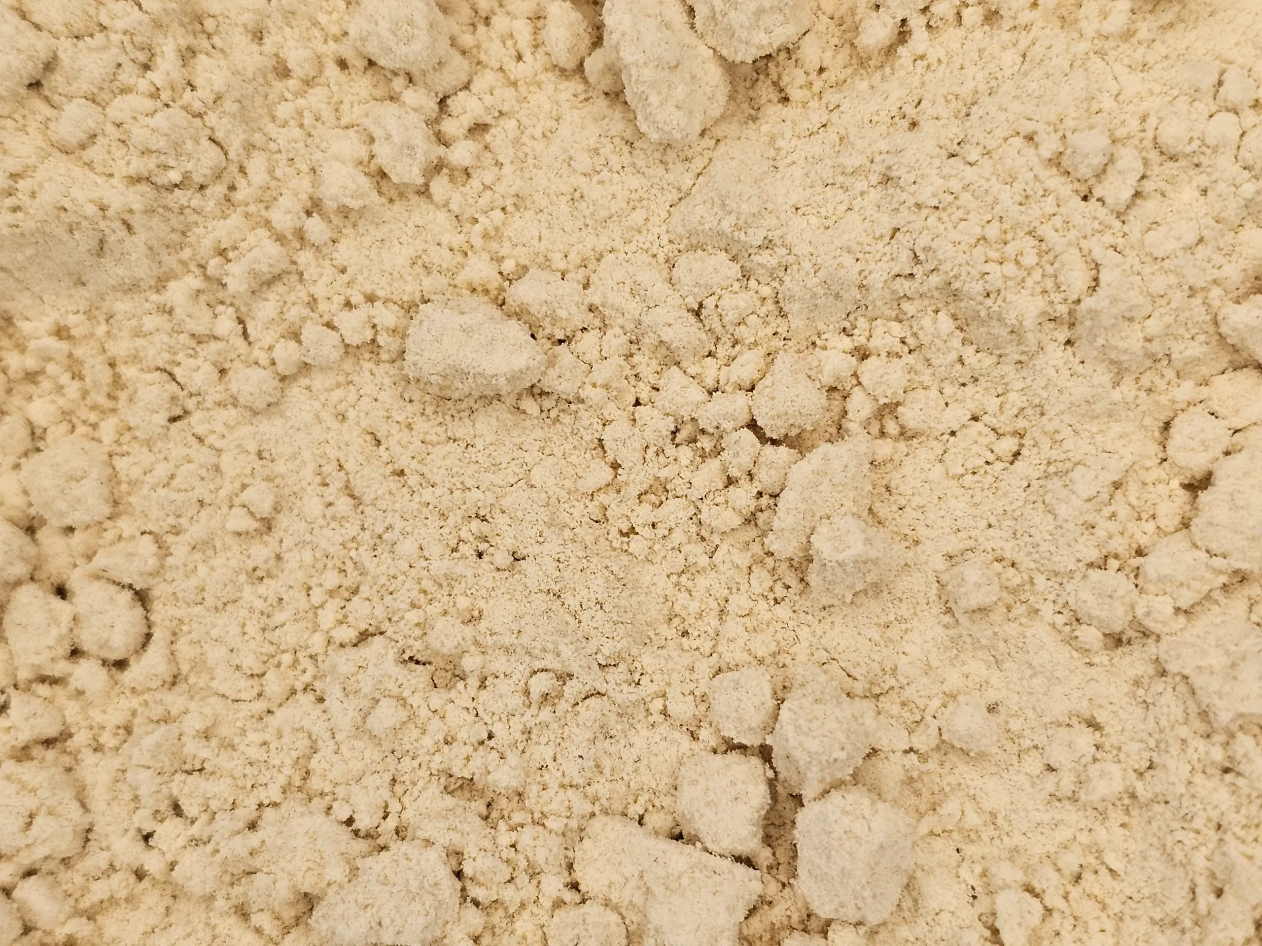 A mound of fine, pale yellow De-oiled Mustard Flour, showcasing its smooth texture.