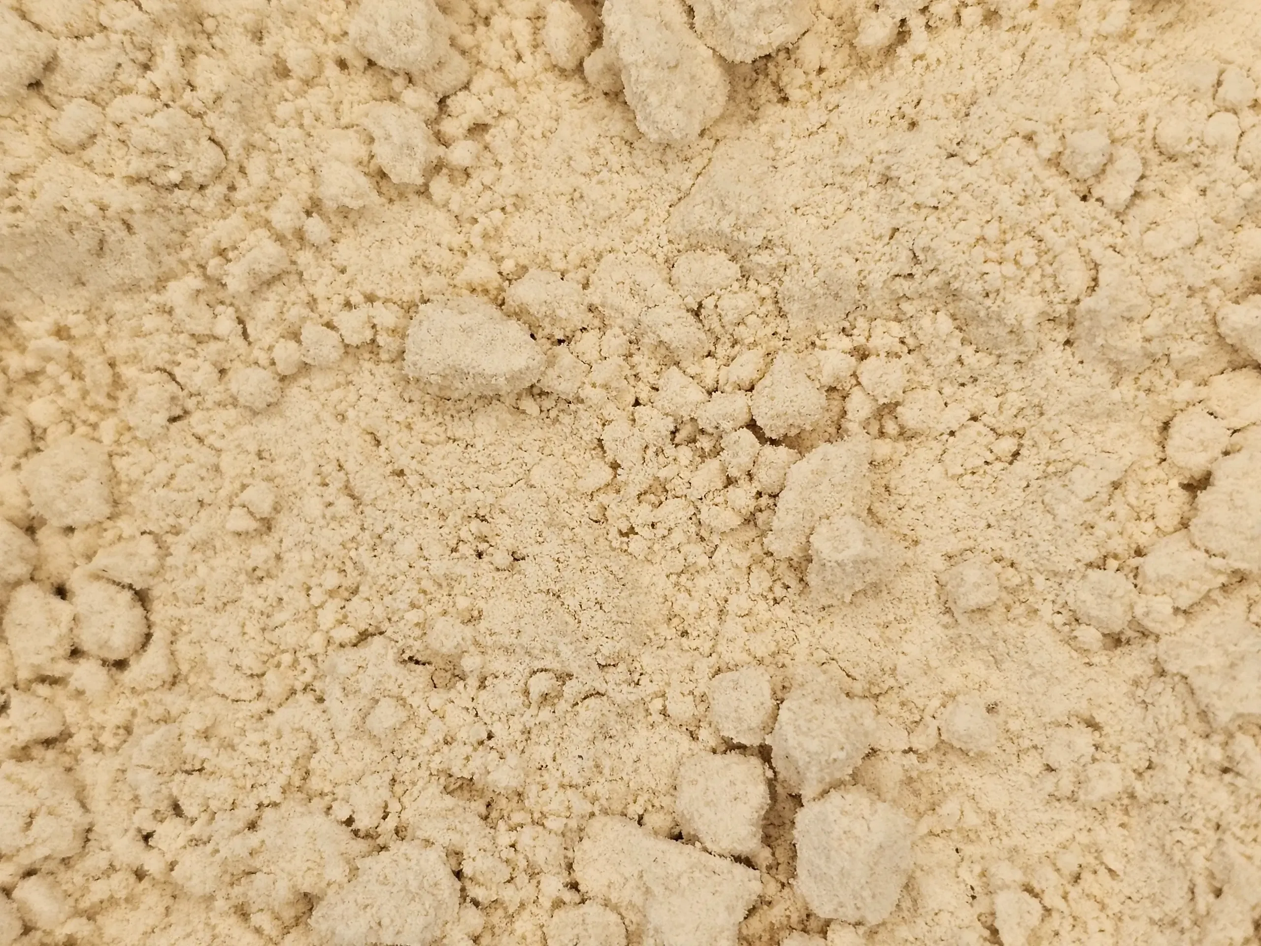 A mound of fine, pale yellow De-oiled Mustard Flour, showcasing its smooth texture.