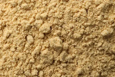 A close-up of coarse Whole Ground Yellow Mustard, showing its granular texture and rich yellow color.