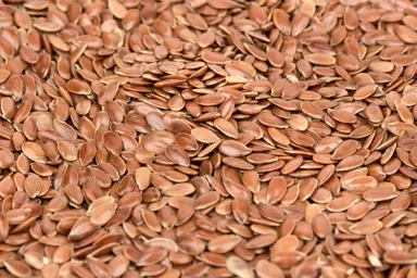 A close-up of rich, brown flax seeds, showcasing their deep color and smooth, shiny surface.