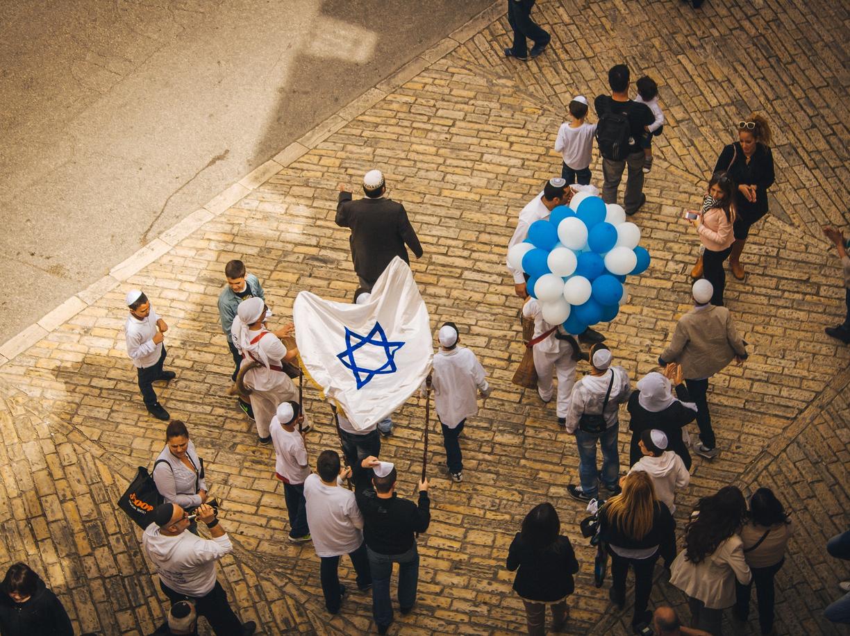Crowd gathered in a Jerusalem square carrying the Israeli flag