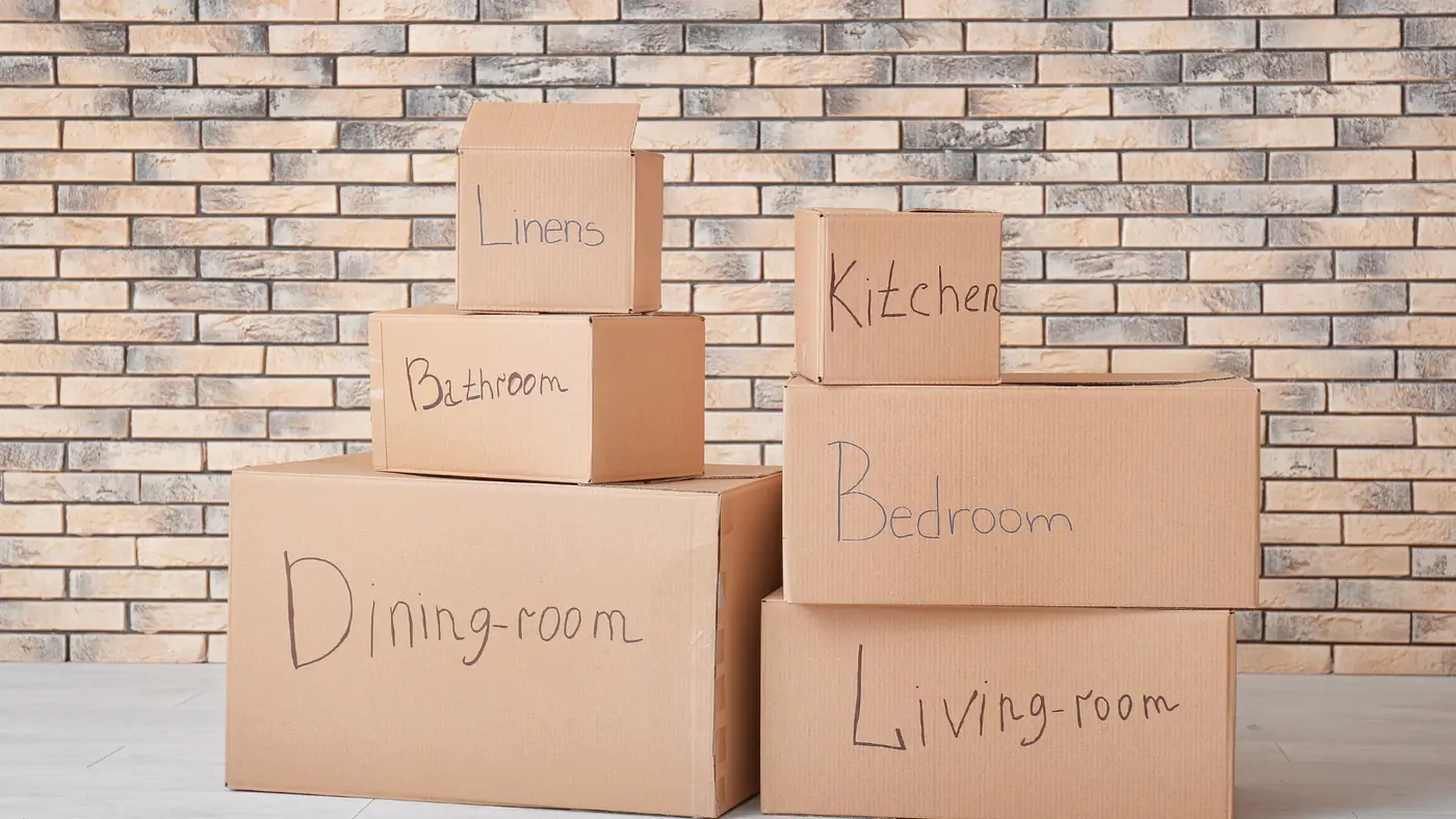 Cardboard moving boxes labelled by room for organised unpacking.