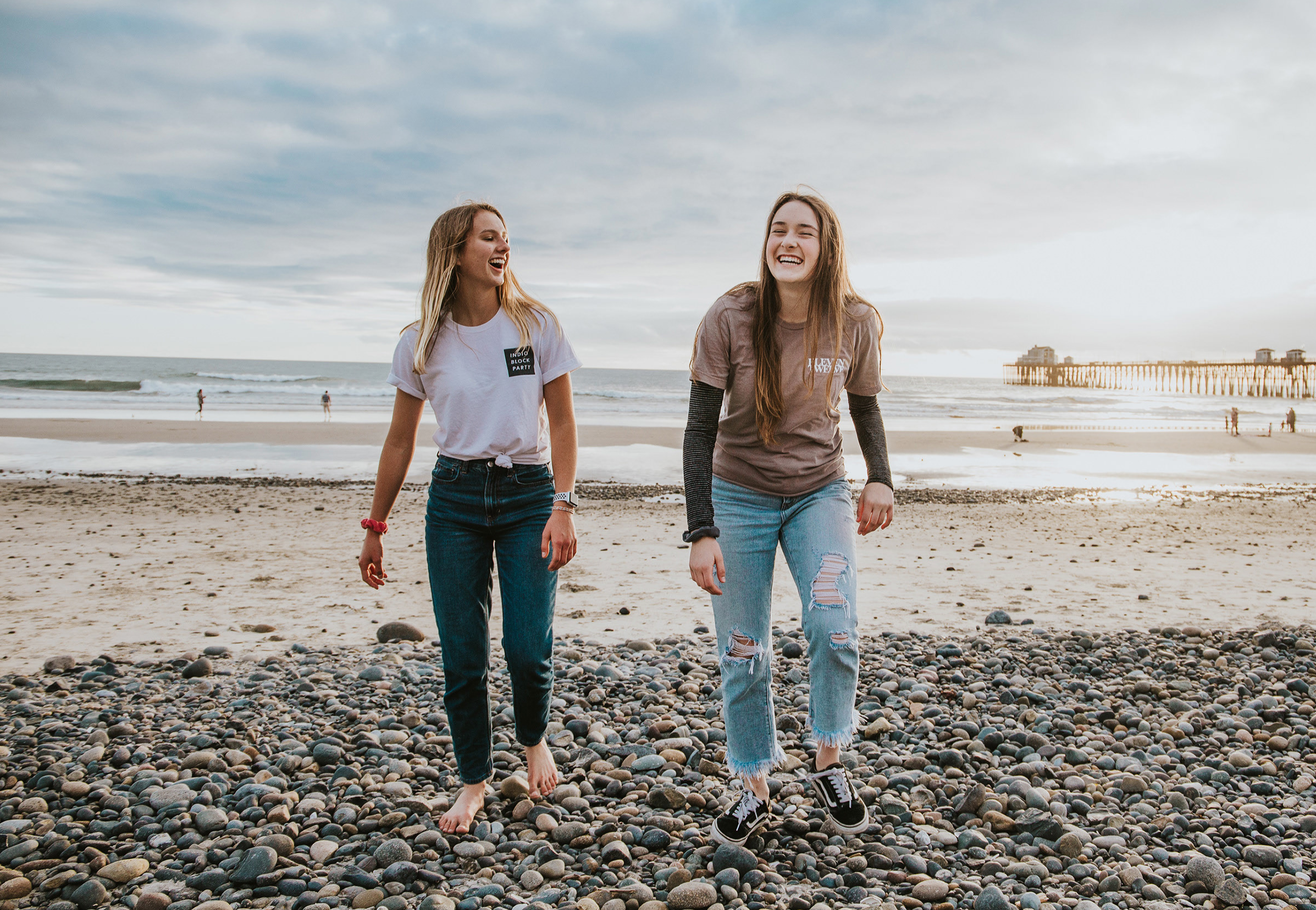To unge jenter smilende på en strand. Foto