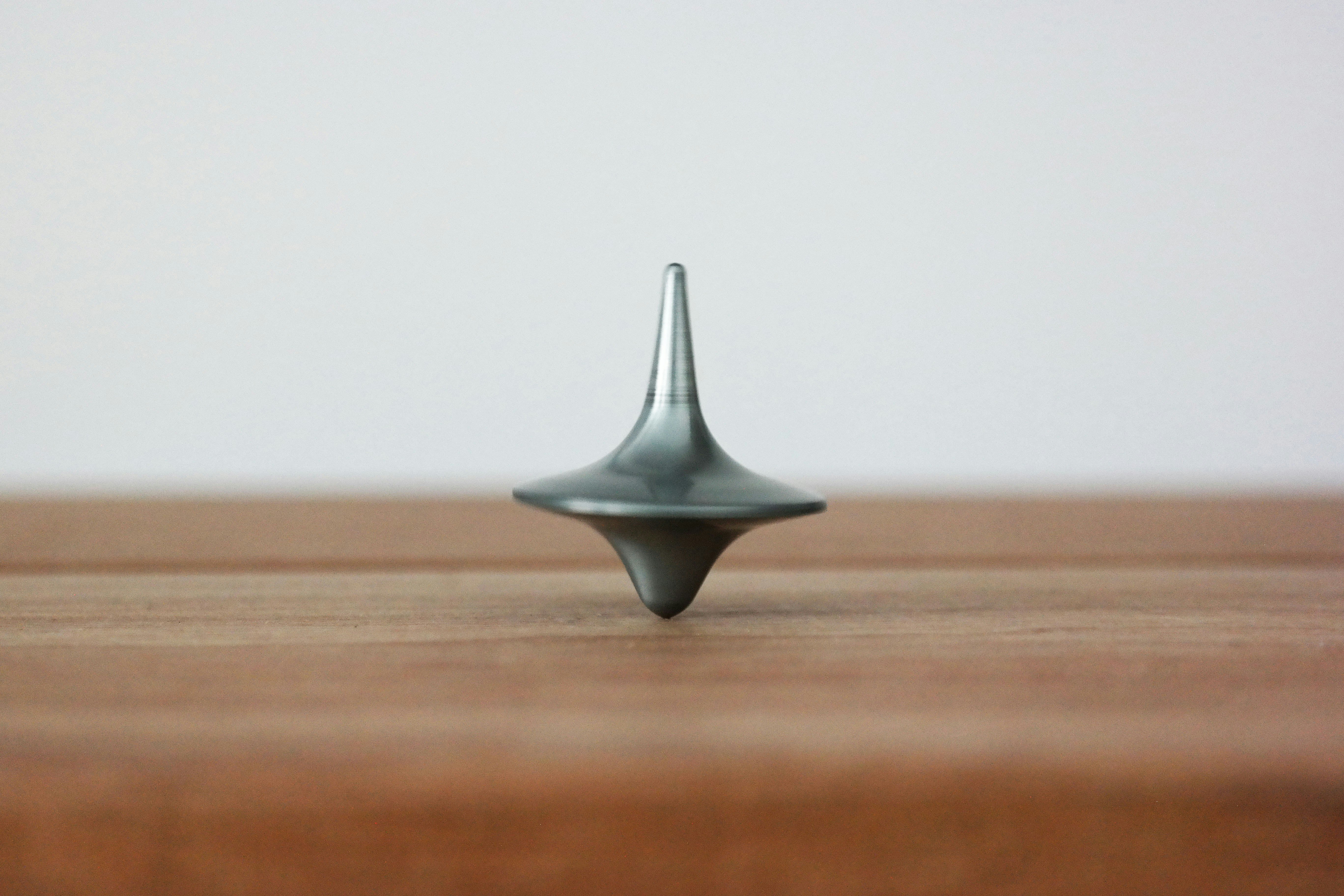 a metal spinning top is sitting on top of a wooden table .