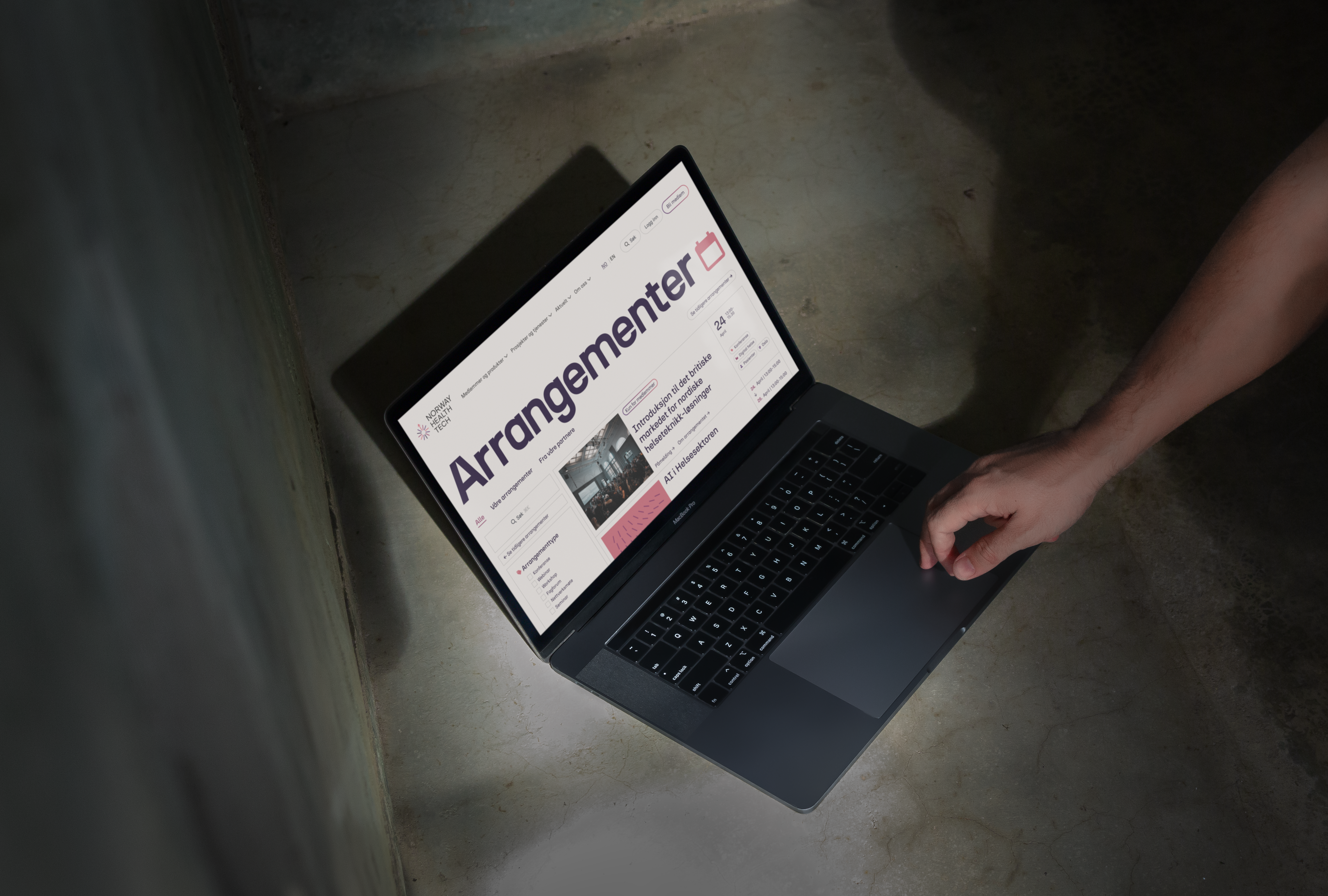 a person is typing on a laptop that says arrangementer on the screen