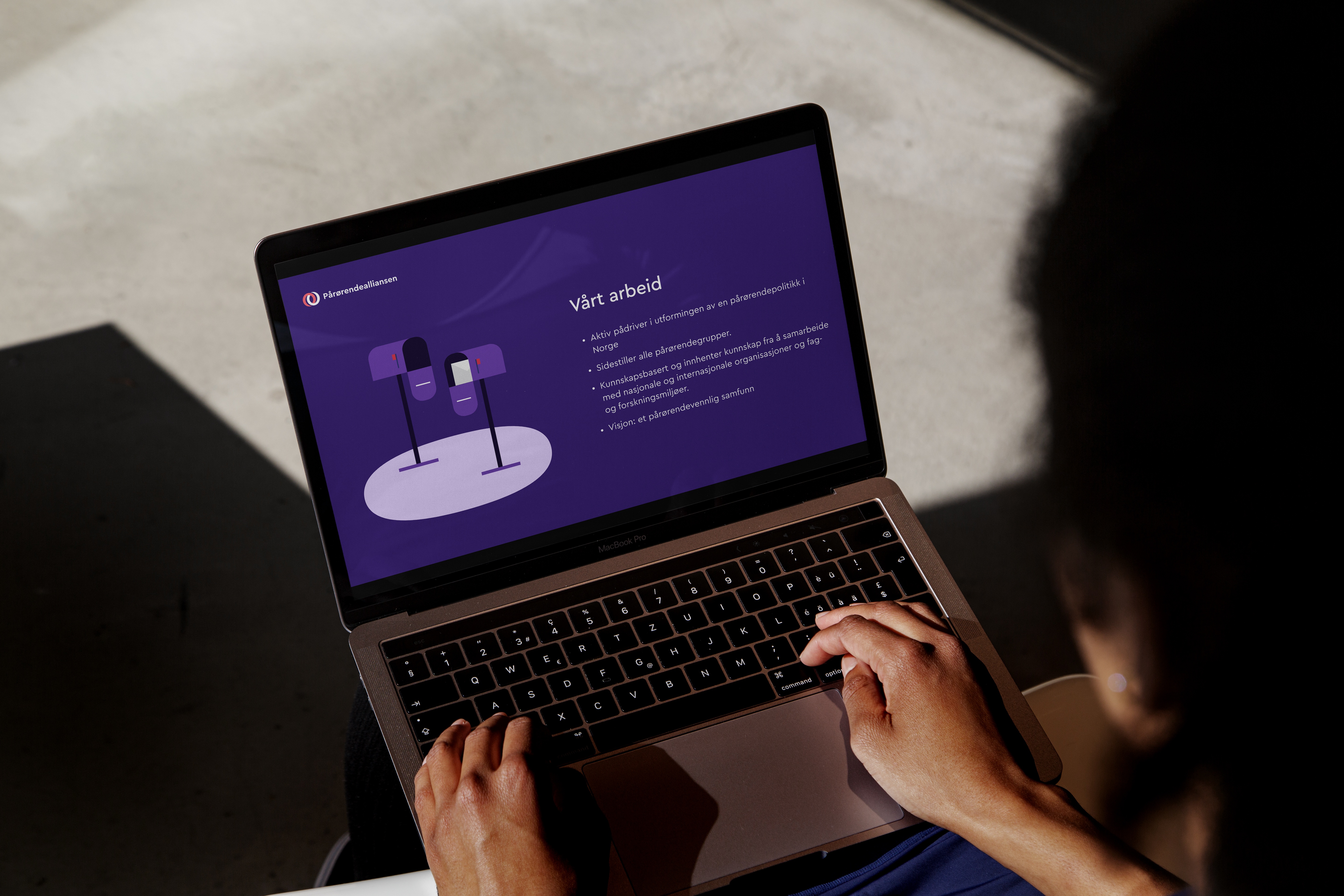 En person sitter med en dataskjerm med lilla fargetema, illustrasjon og tekst med tittel "Vårt arbeid"