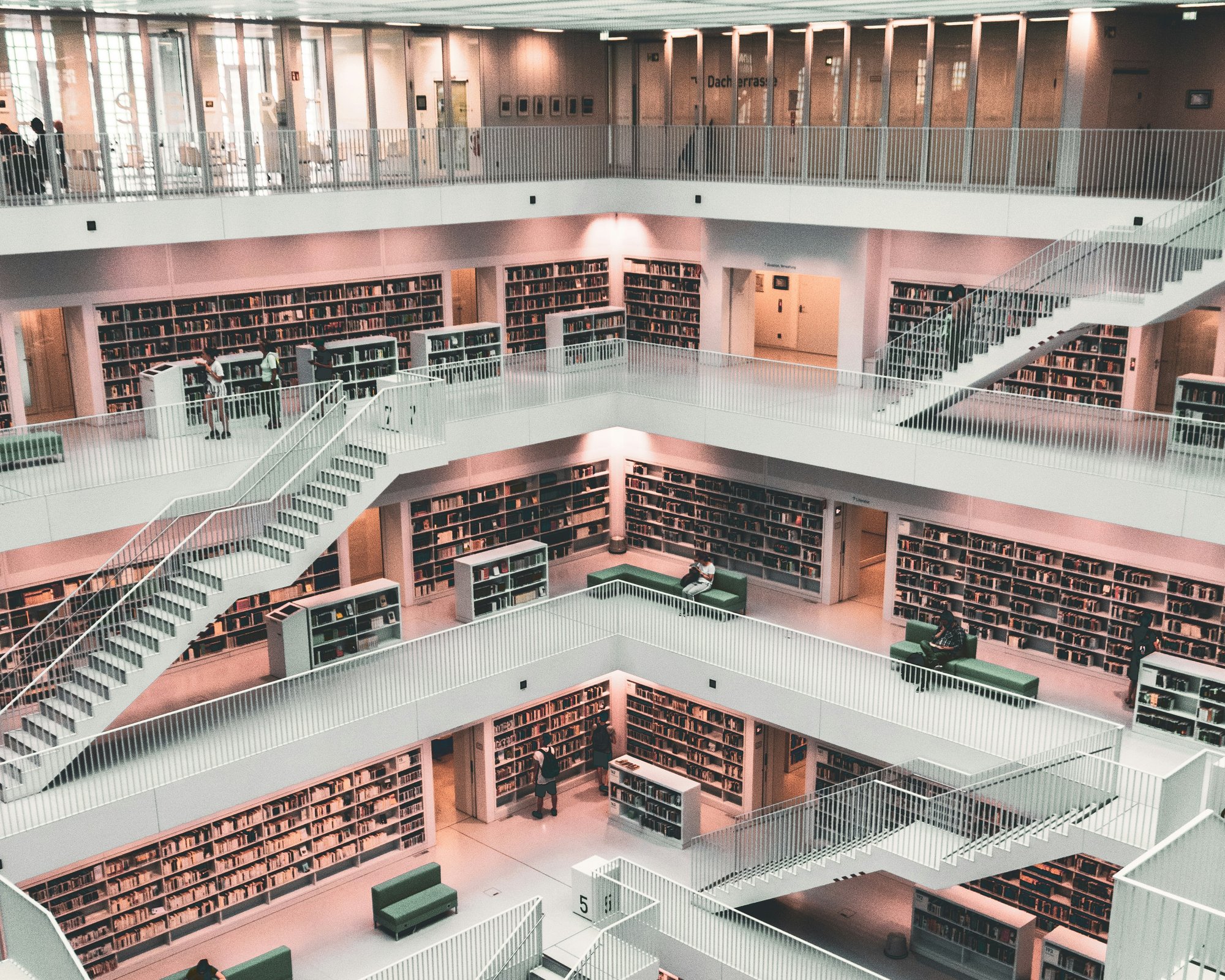 Et bibliotek sett overinfra med flere etasjer og hvite hyller. Foto.