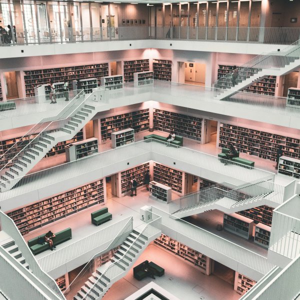 Et bibliotek sett overinfra med flere etasjer og hvite hyller. Foto.