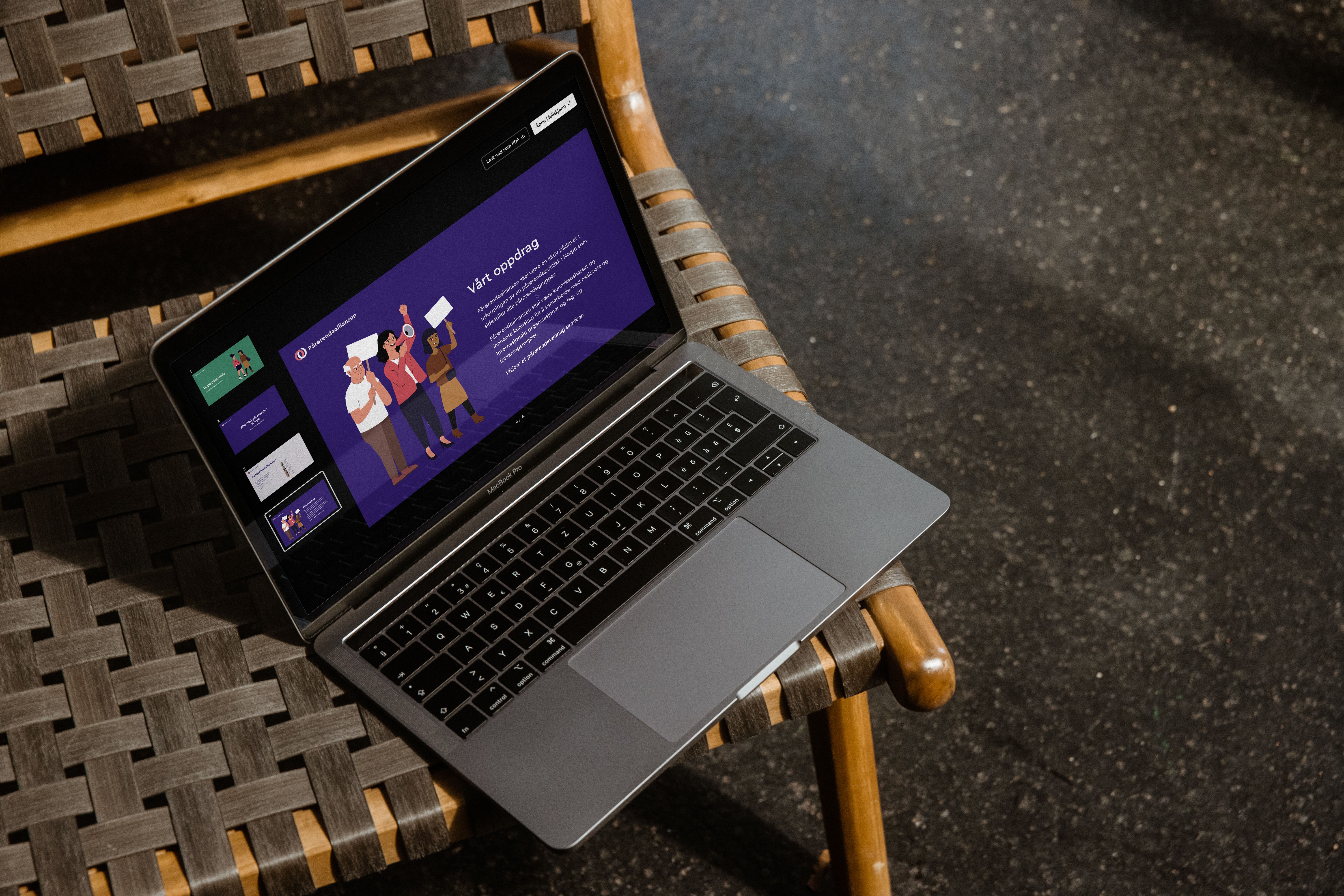 en bærbar datamaskin ligger på toppen av en tre stol. Viser presentasjonsgeneratoren som viser en slide og oversikt over slides på siden