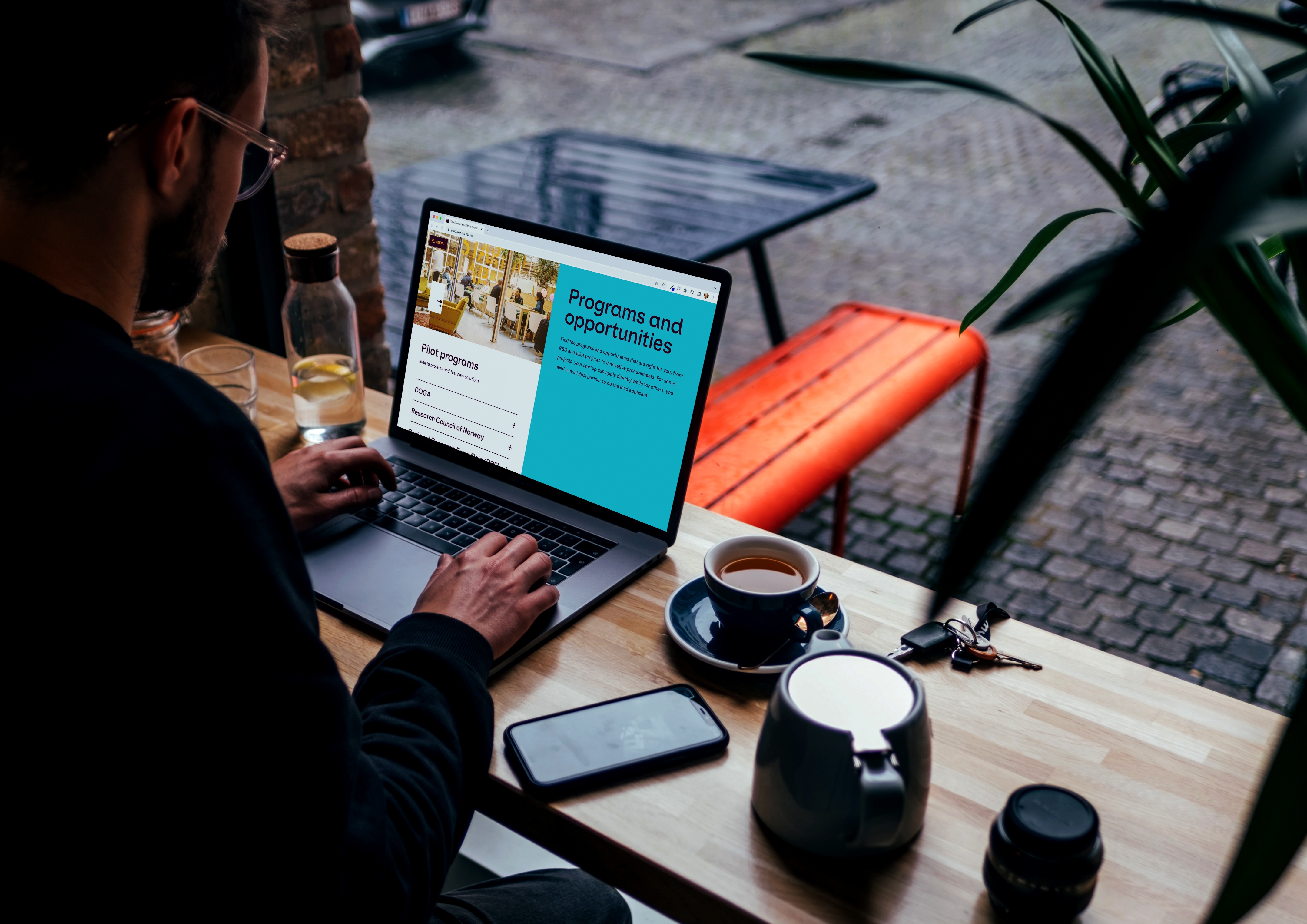 Person drikker kaffe og ser på nettsiden. Foto.