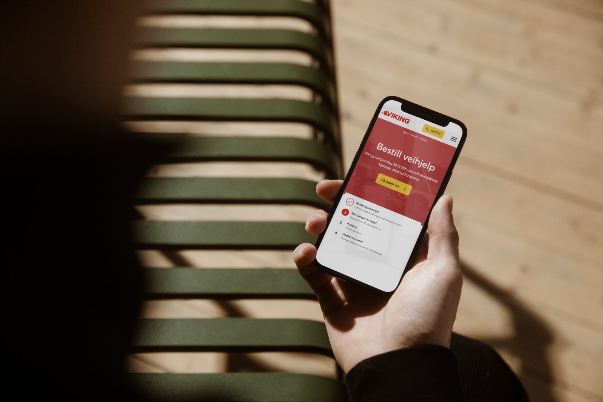 En person holder en mobil med Bestill veihjelp