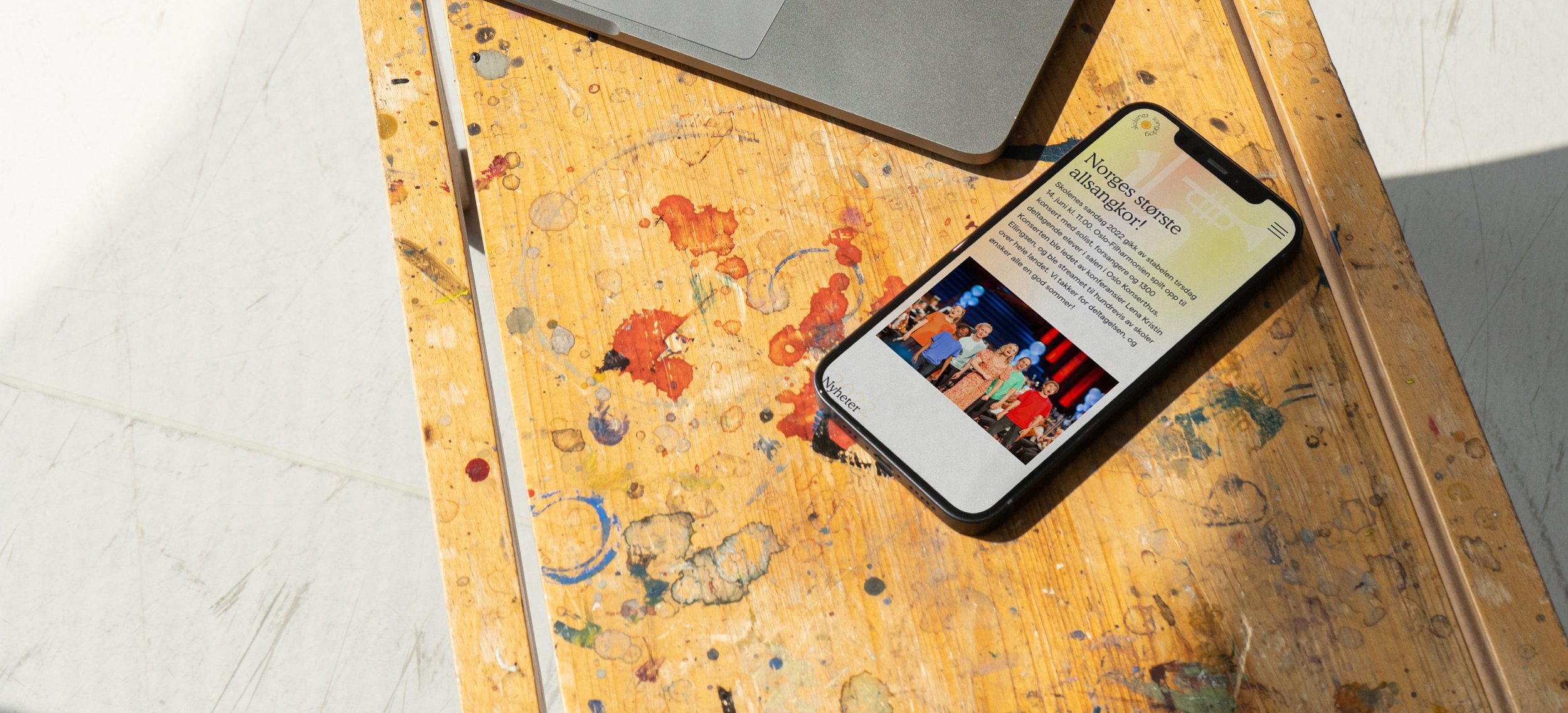 a cell phone is sitting on a wooden table next to a laptop .