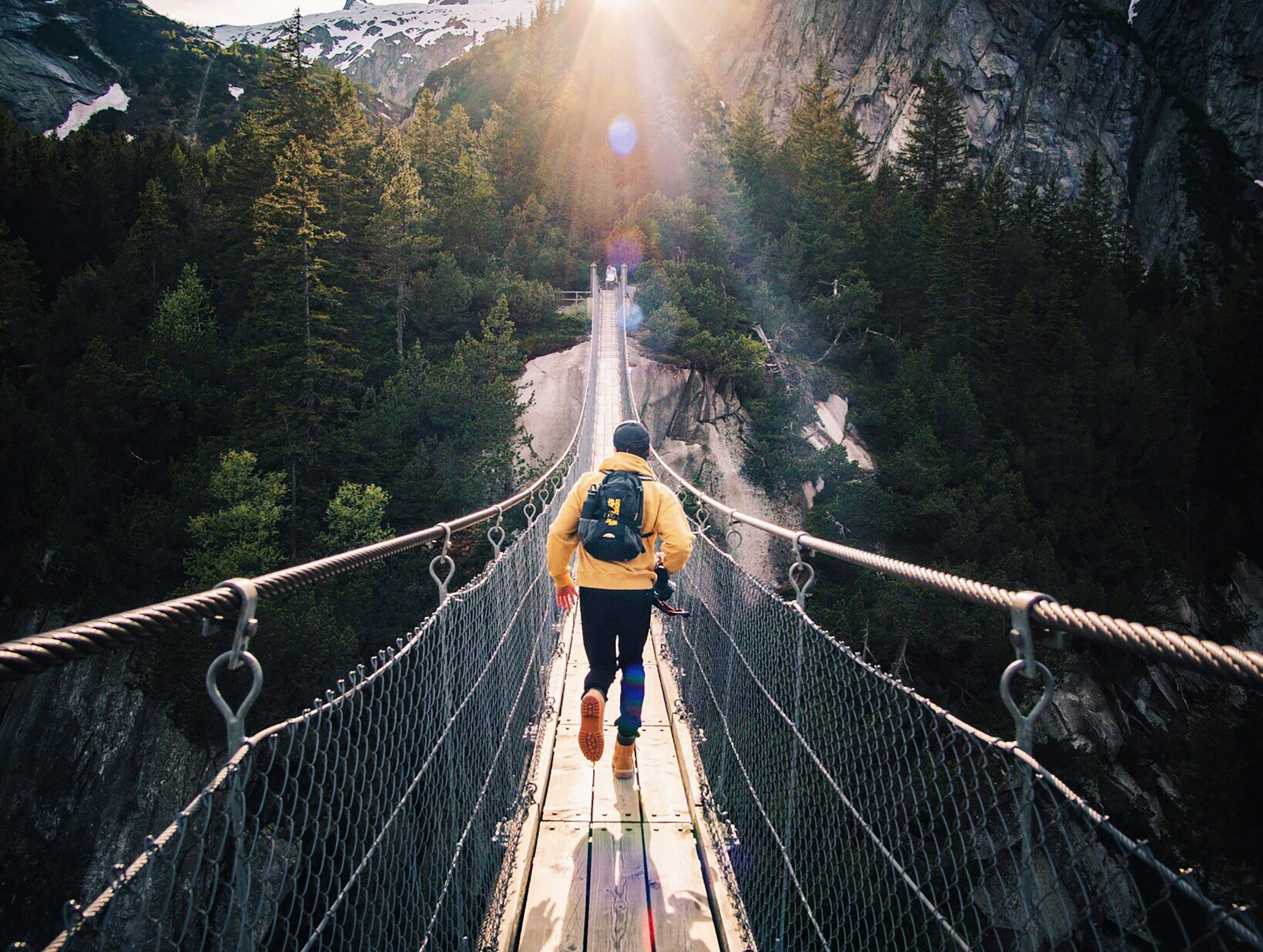 en person går over en hengebro i fjellene