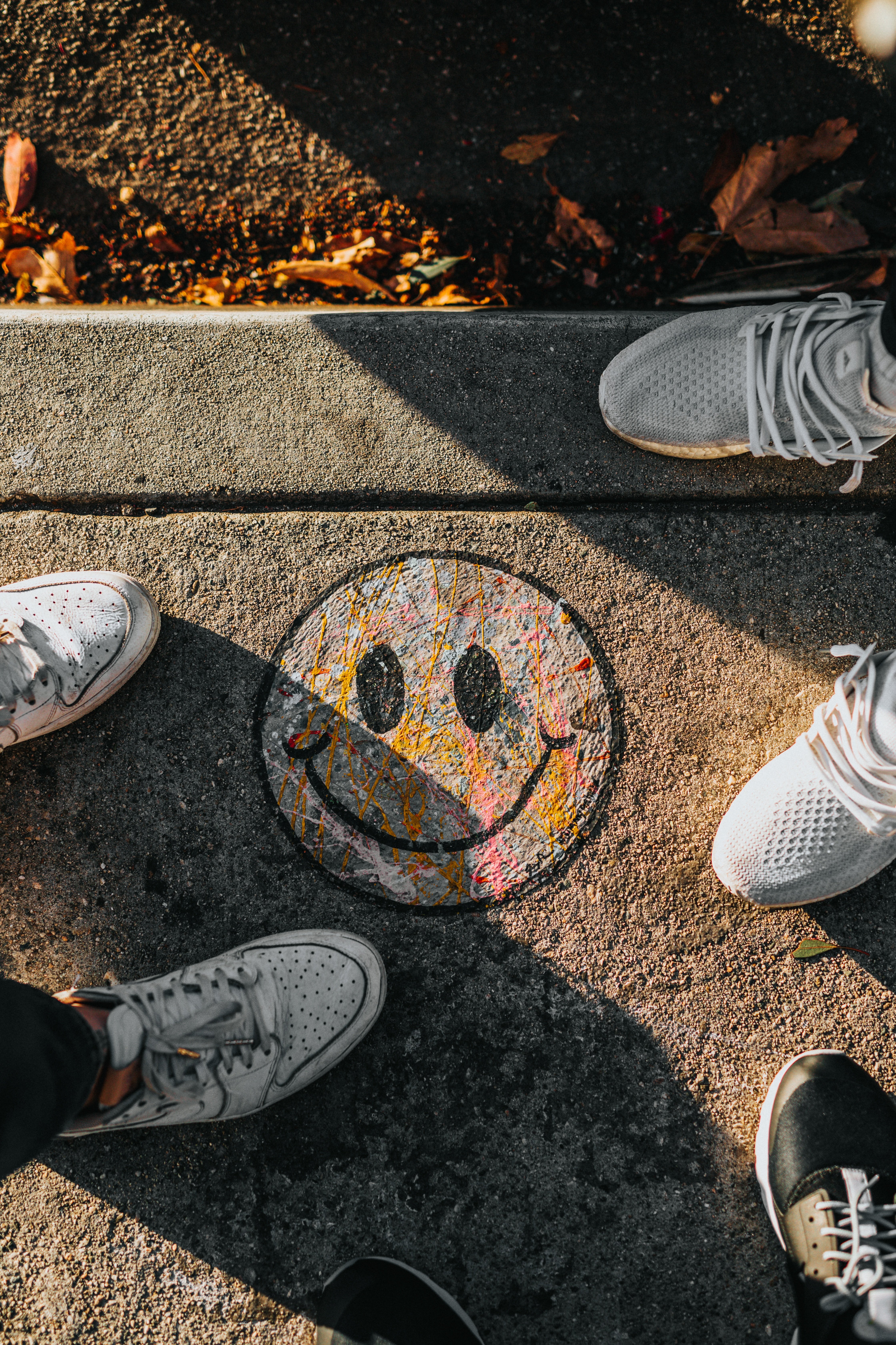 a group of people standing next to a smiley face painted on the sidewalk .