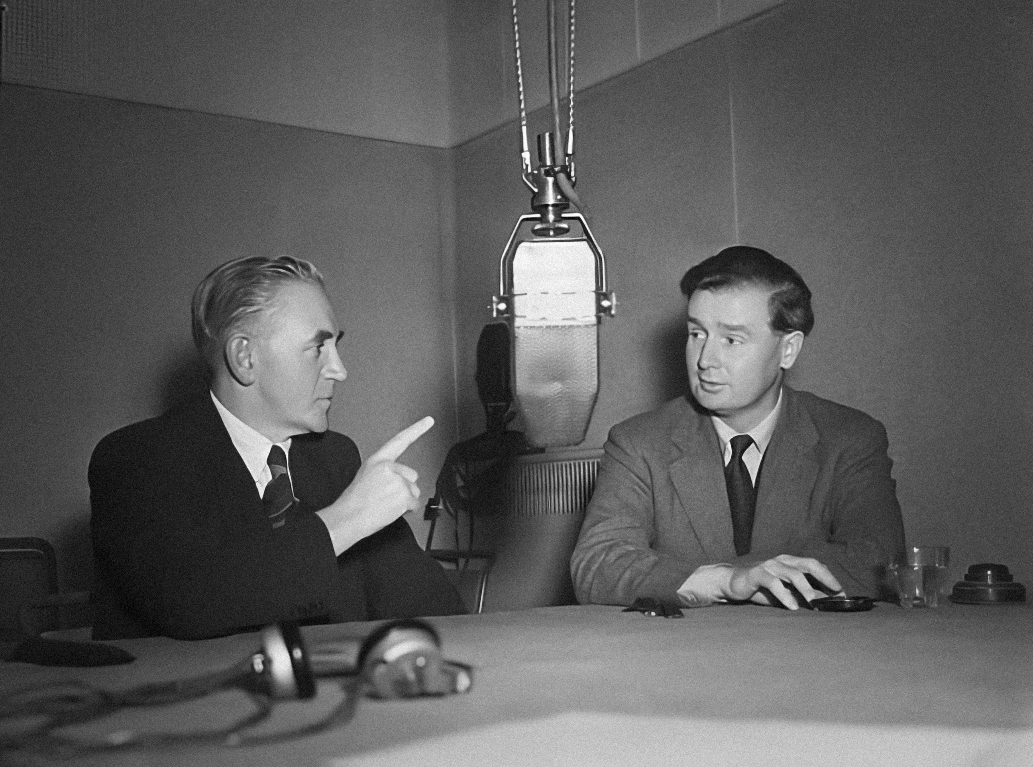 To menn som diskuterer med hverandre i et 50 talls studio. 