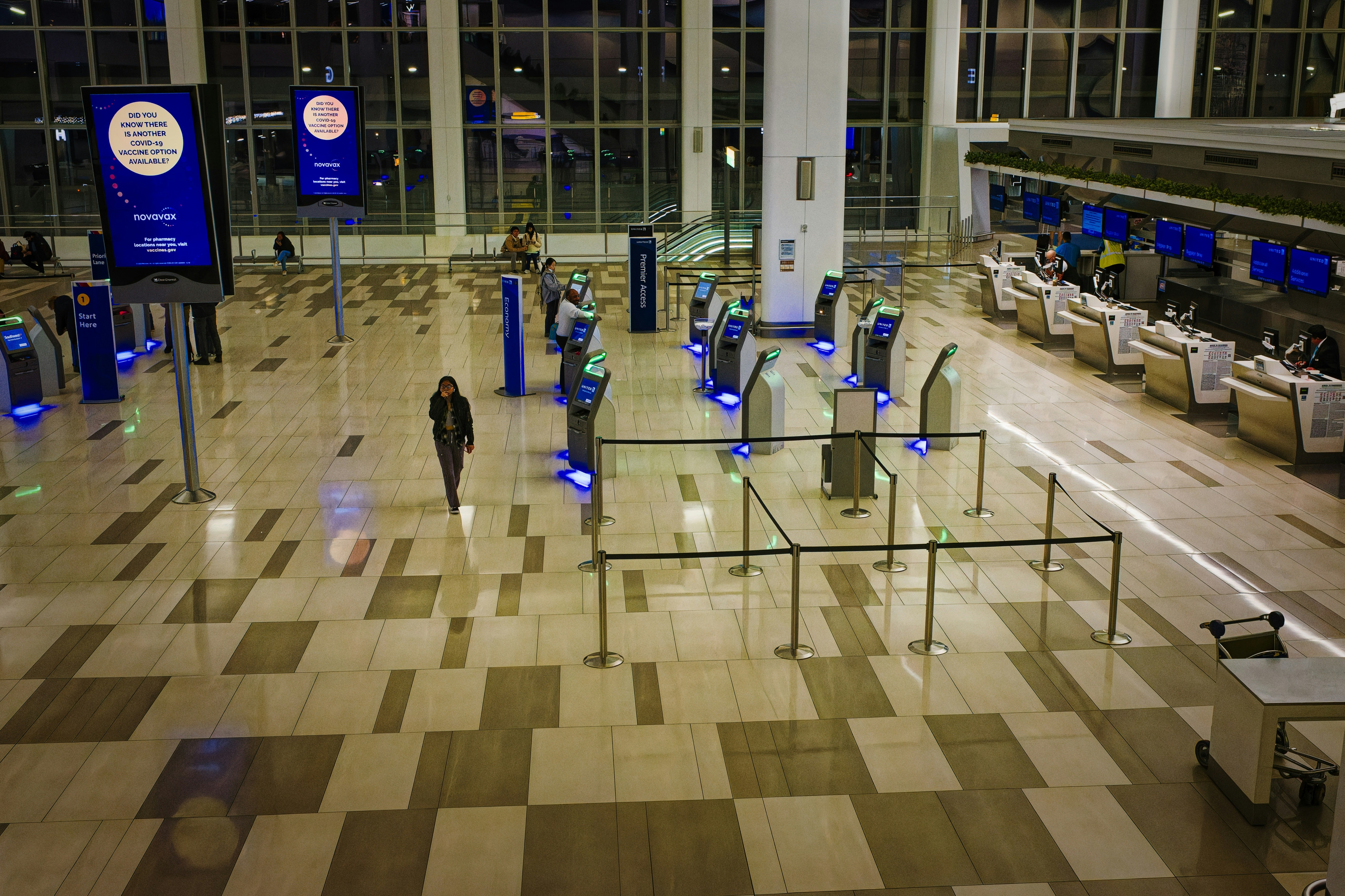 a woman is walking through an empty airport terminal at night .