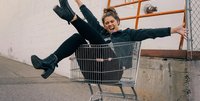 Dame sitter i handlevogn og smiler