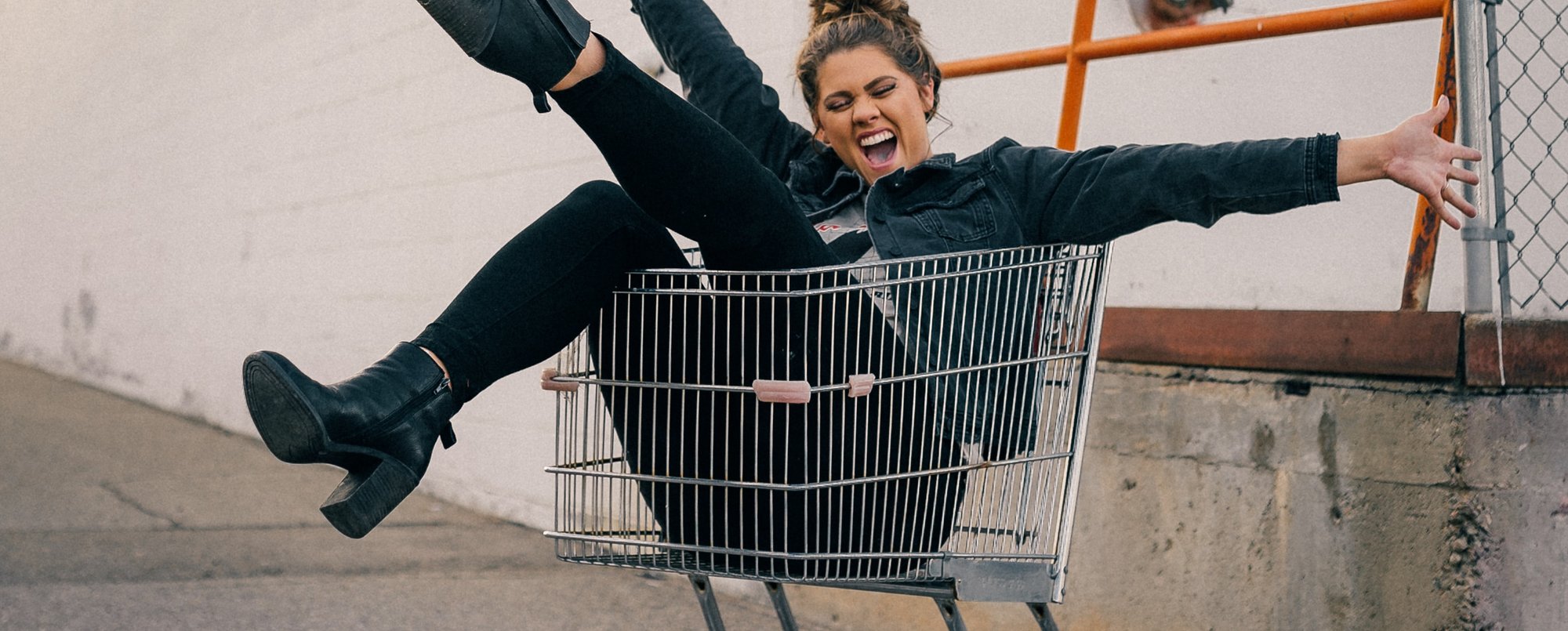 Dame sitter i handlevogn og smiler