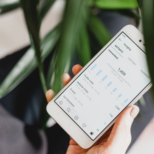 Person holder mobil som viser et utdrag av Google Analytics og webstatistikk