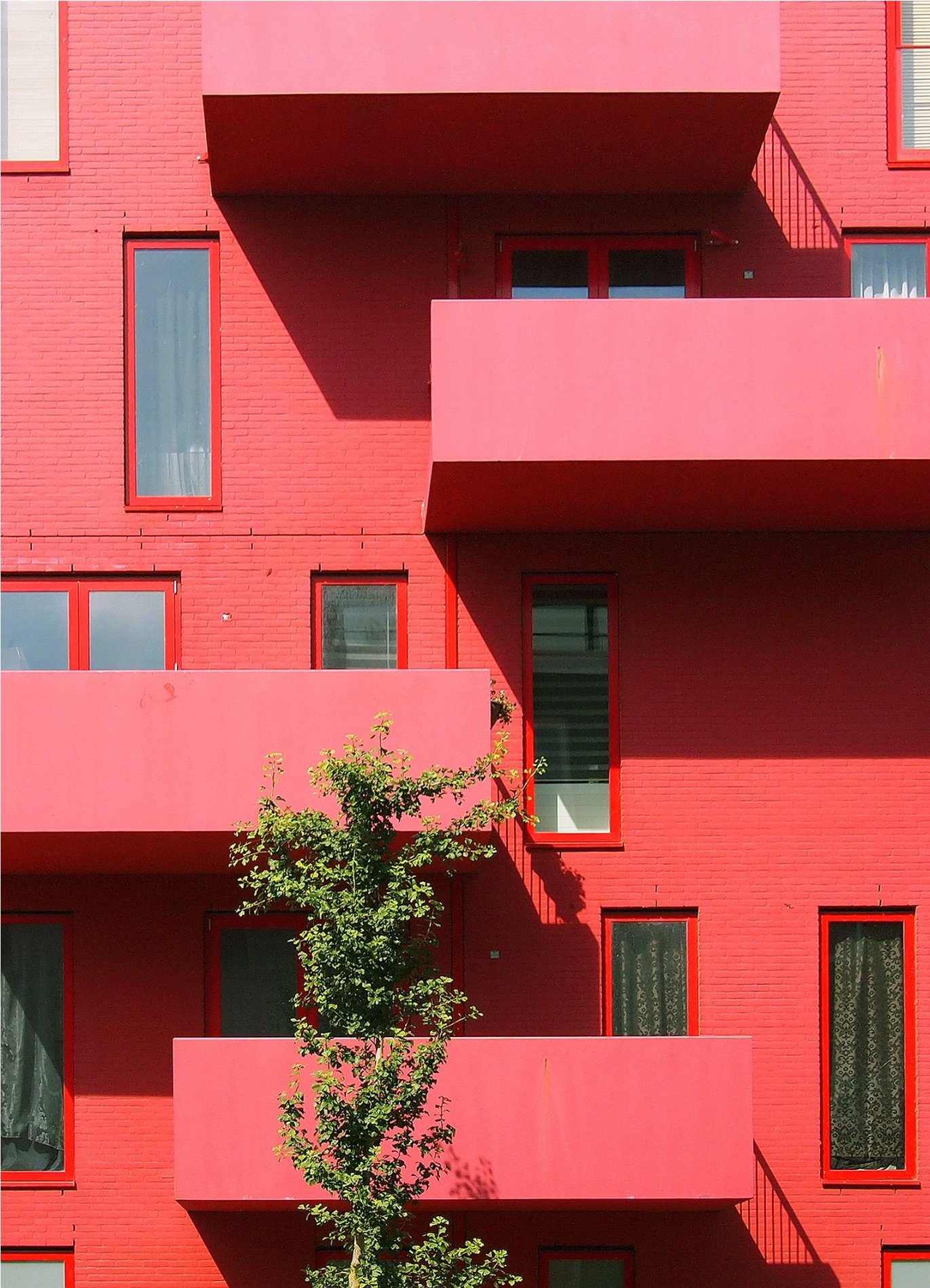 Rød bygning med fire balkonger. Kreativ arkitektur. Foto