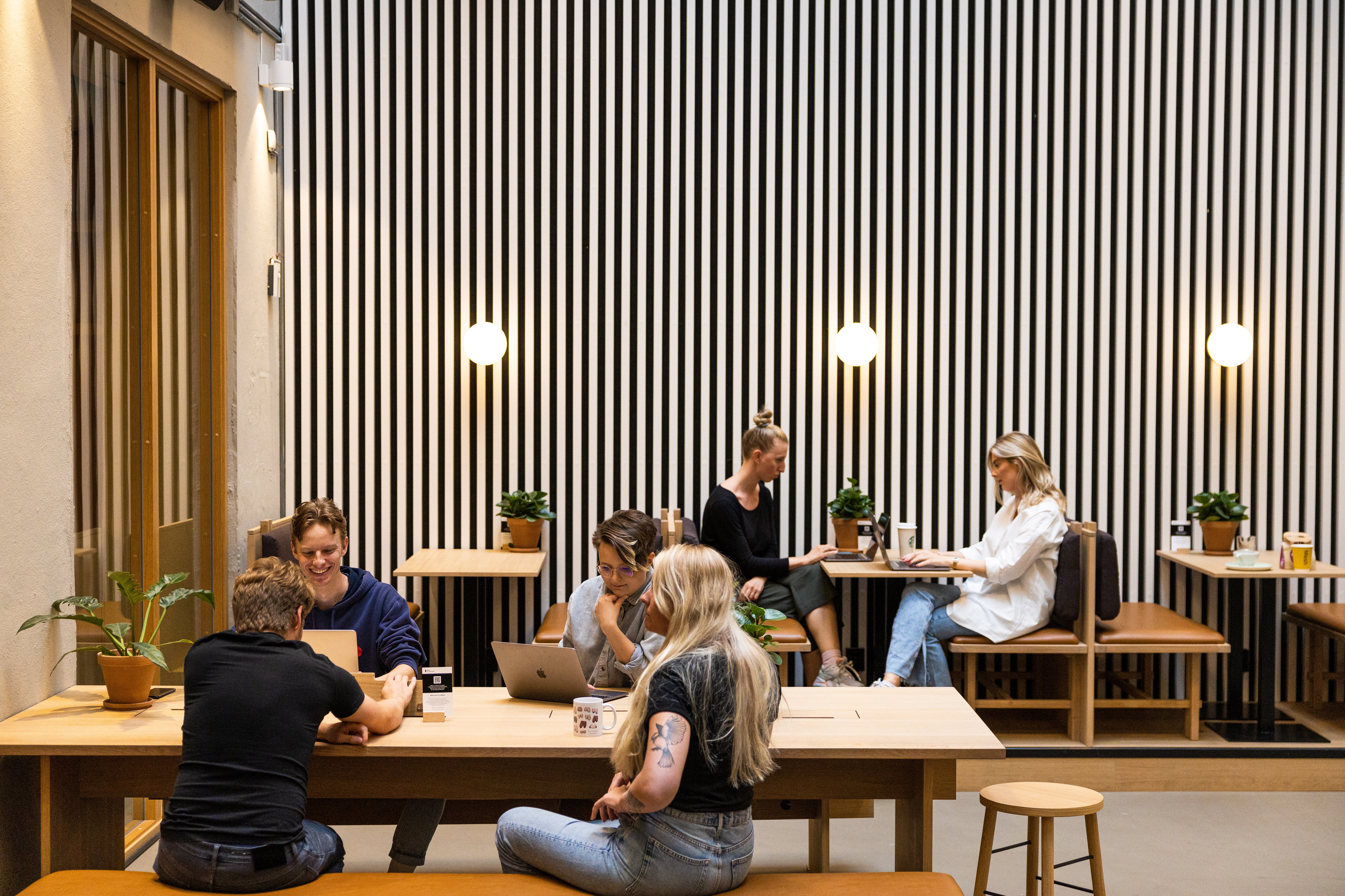 a group of people are sitting at tables in a room with a striped wall .