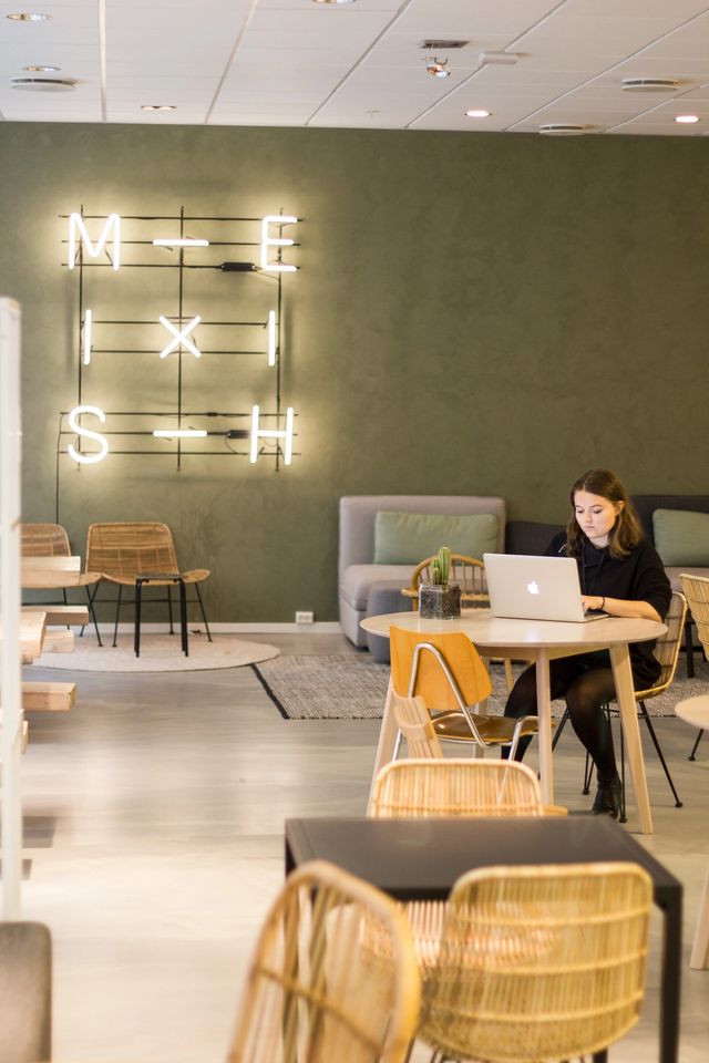Vilde i Kult Byrå sitter på et bord, kosentrert og jobber på en macbook