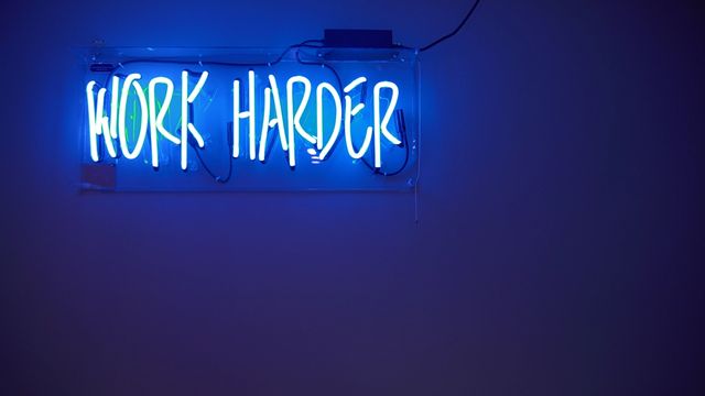 Neon lyskilt der det står "Work Harder"