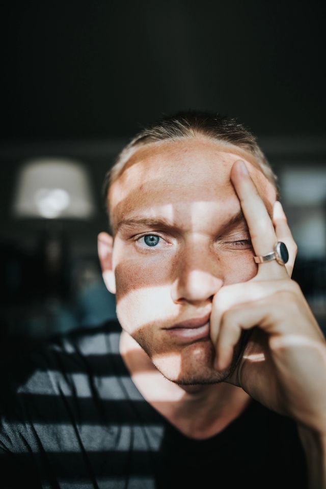 Sliten ung gutt holder seg på hodet og ser inn i kamera. Foto