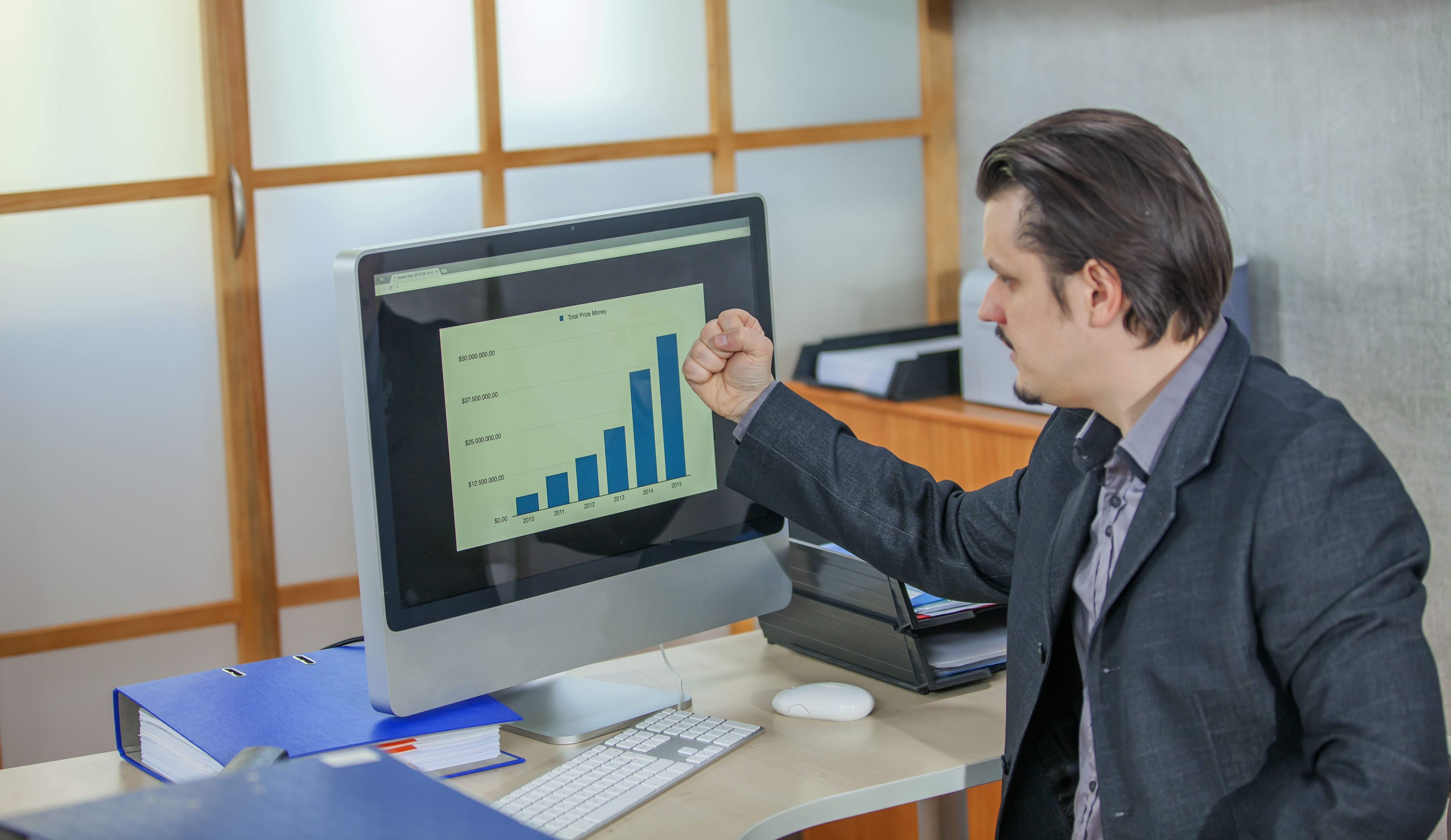 a man in a suit pointing at a computer screen