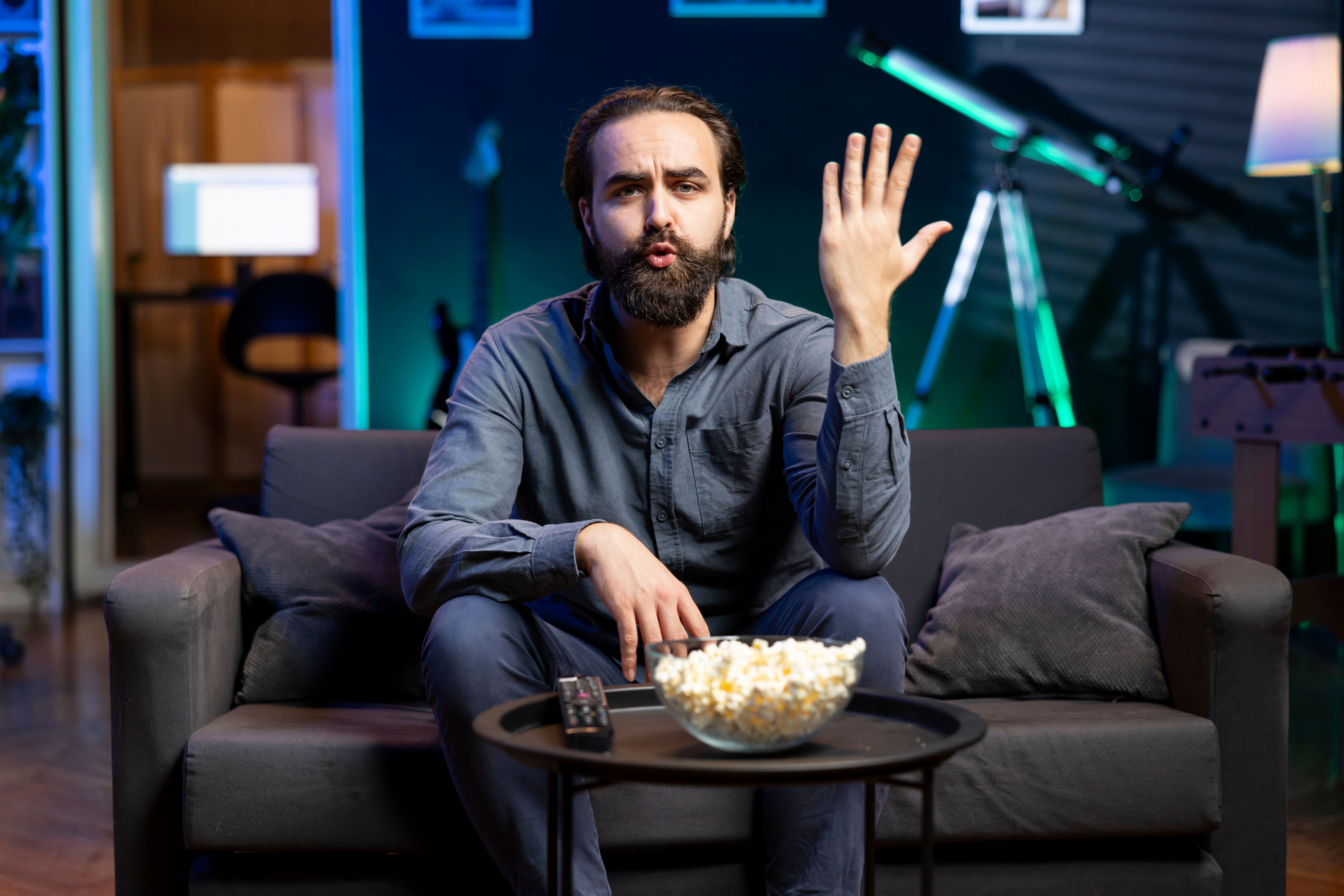 a man sitting on a couch with a bowl of popcorn