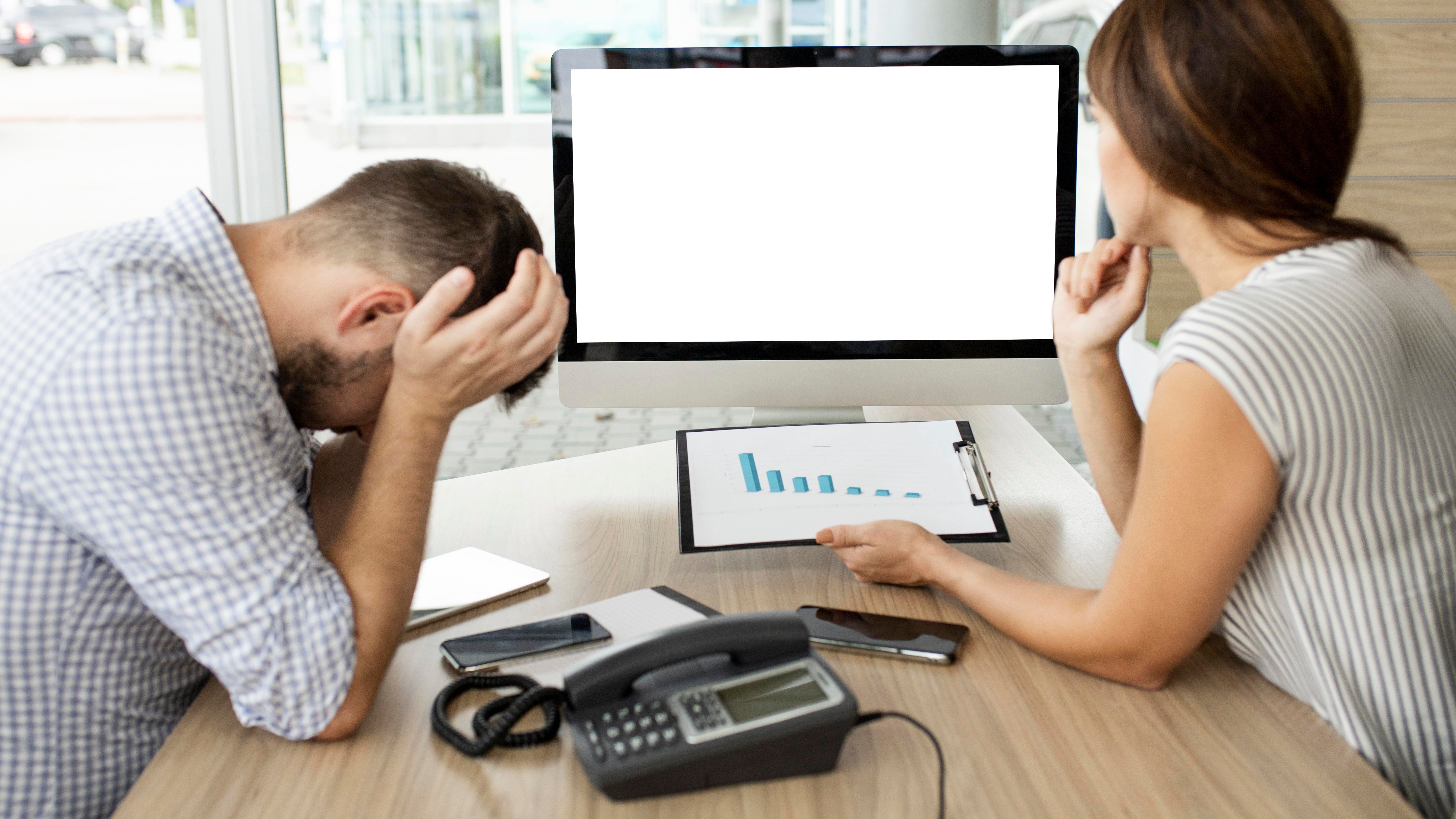 a man and woman sitting at a desk with a computer