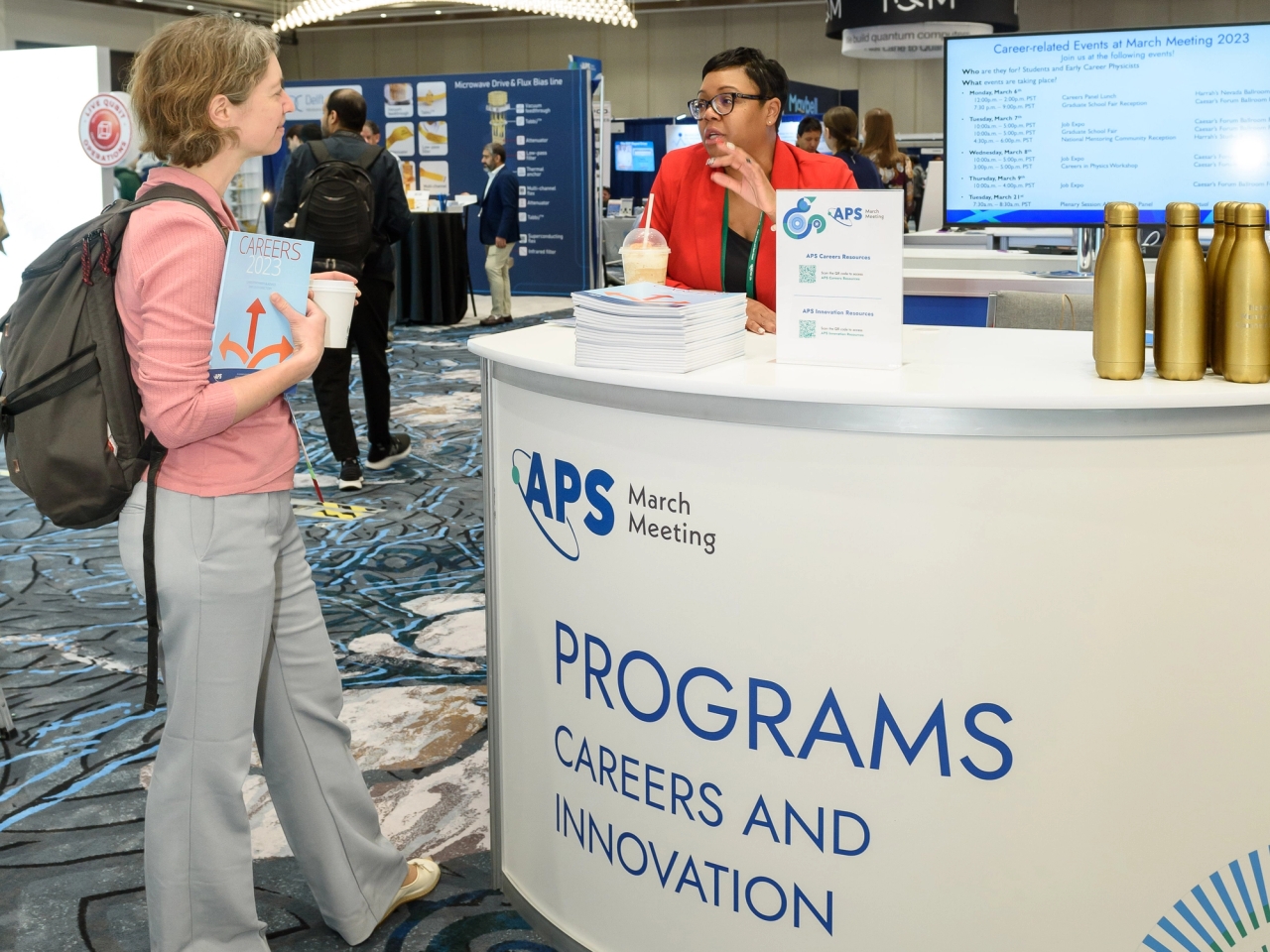 March Meeting attendee in conversation with an APS Programs booth staffer in the exhibit hall