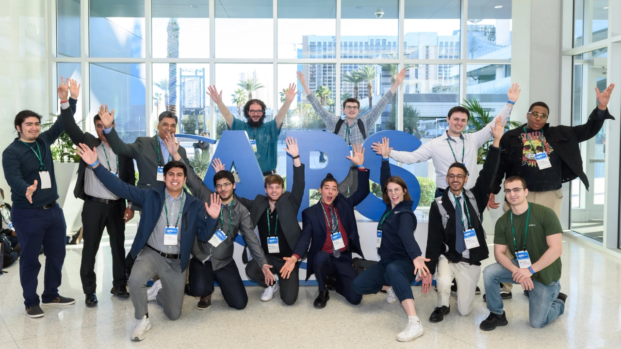 March Meeting attendees posing with a display of the APS logo