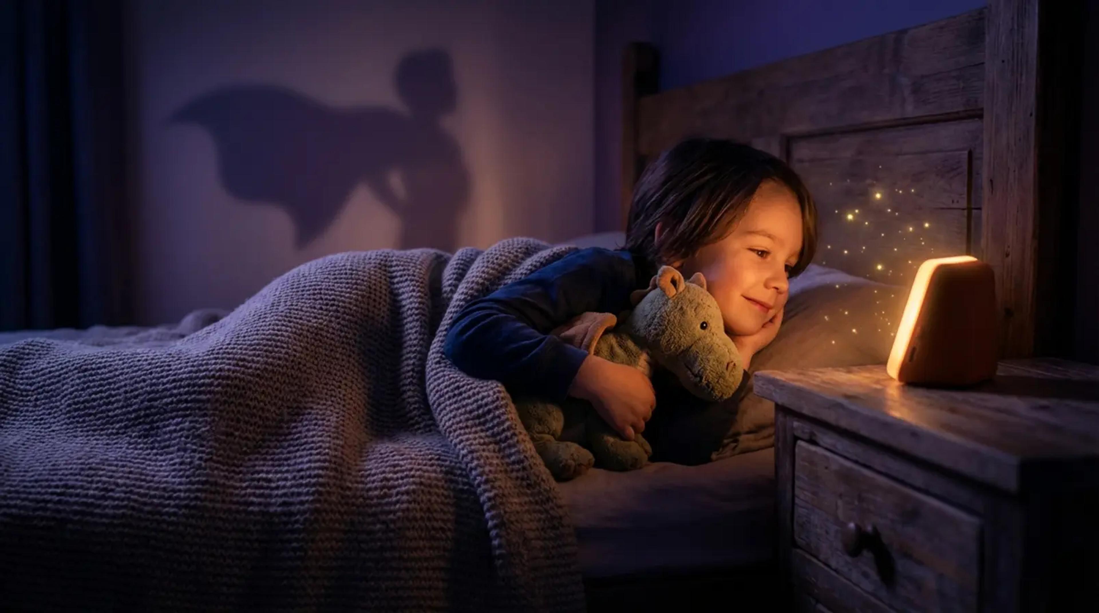 A young child lying peacefully in bed at night, listening to a glowing screen-free audio player in a magical, cozy bedroom setting.