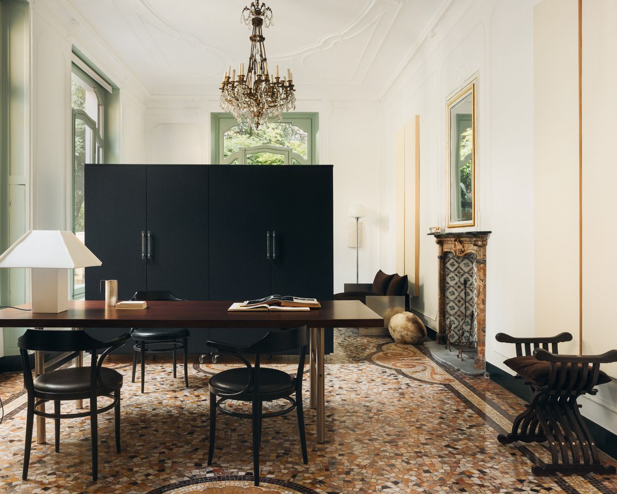 Ein ausgewogenes Schlafzimmer in einer Mailänder Wohnung mit hohen Decken, Marmormosaikboden, skulpturalen Möbeln und markanter architektonischer Kulisse.