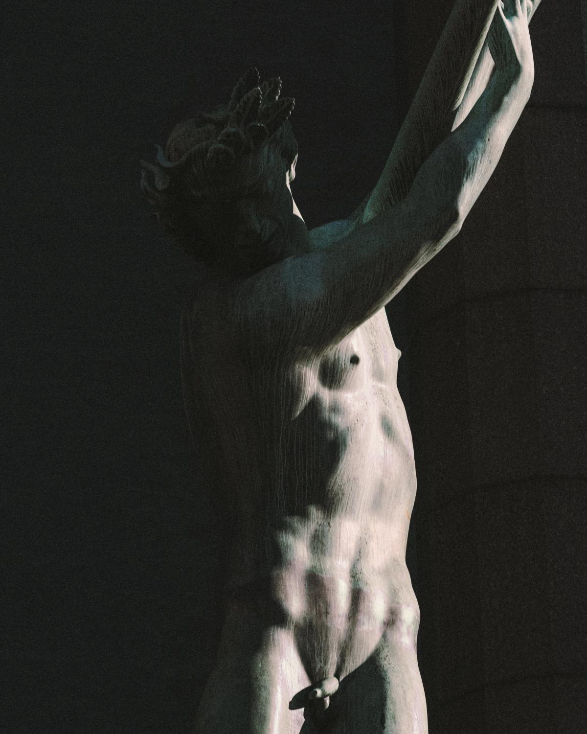 A bronze sculpture of a standing male figure in shadow, captured against the façade of Stockholm Concert Hall.