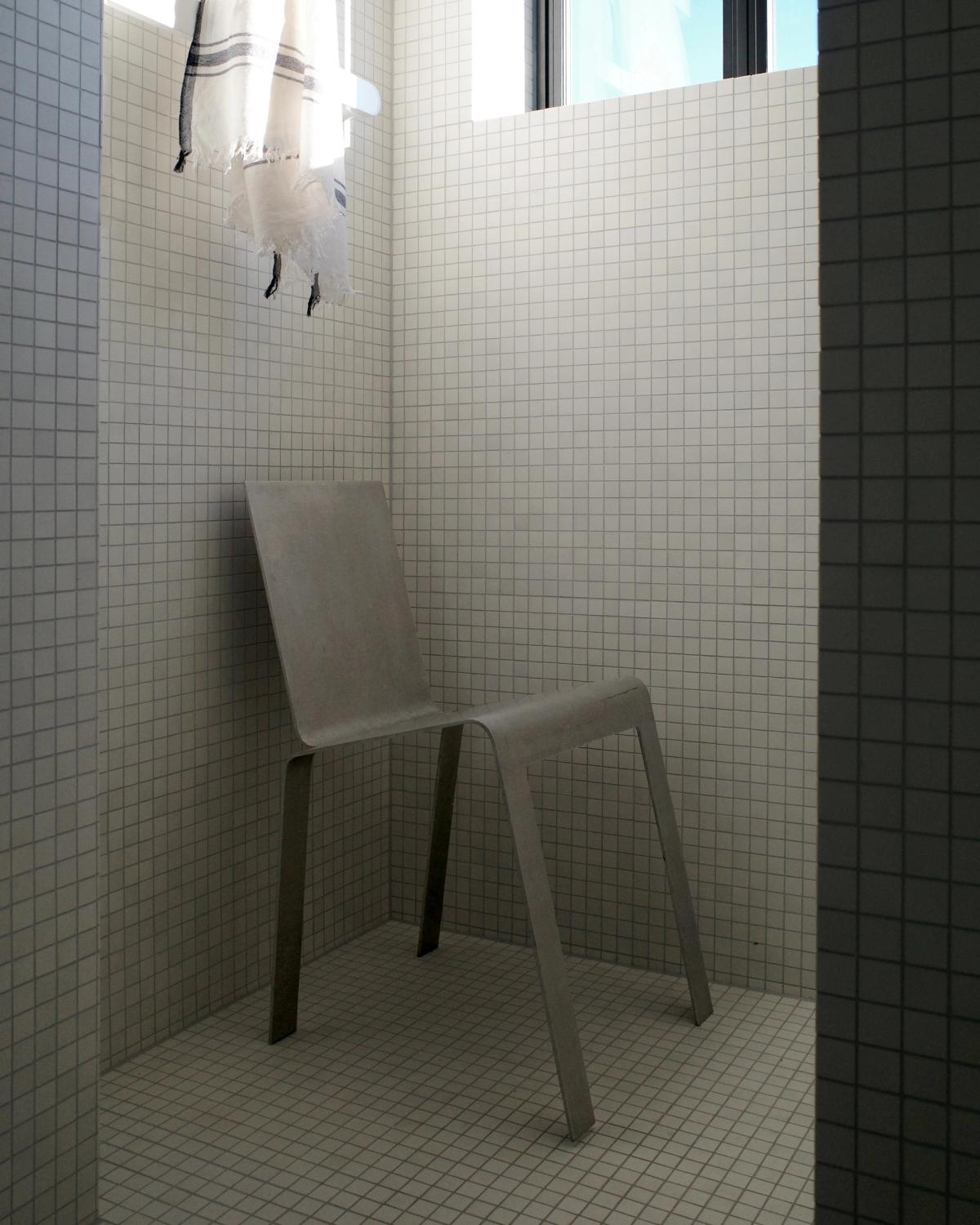 Photograph of a metal chair inside a black and white tiled shower at Monument Store.