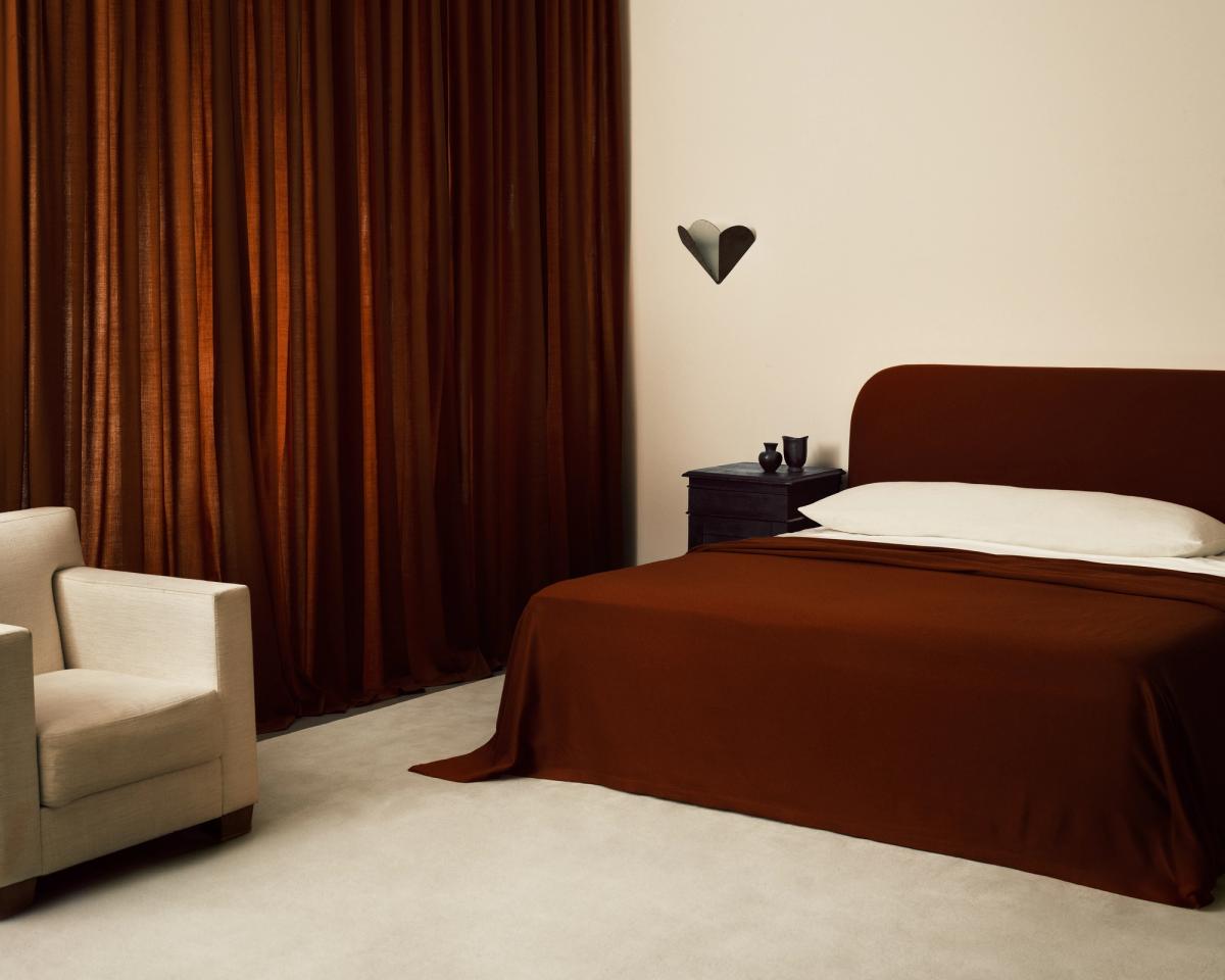 A bedroom featuring Grand rug in Dusty White paired with curtains in a shade of Burnt red.