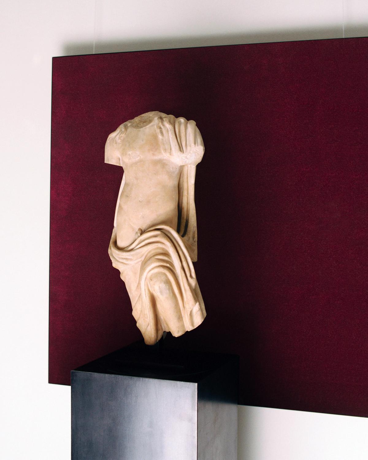 A painting of the Grand rug in Deep Wine hanging on the wall, framed by a marble statue at Galerie Chenel in Paris.